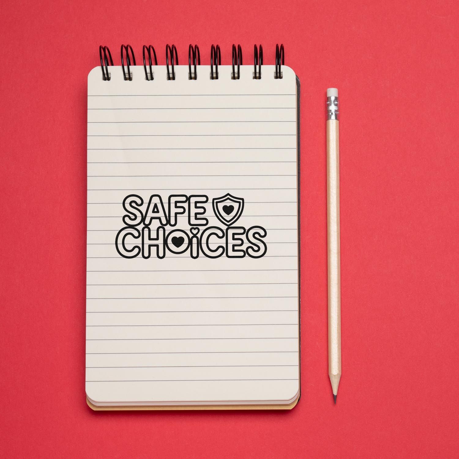 Safe Choices stamp and seal on lined notebook with heart shield, beside a pencil on a red background