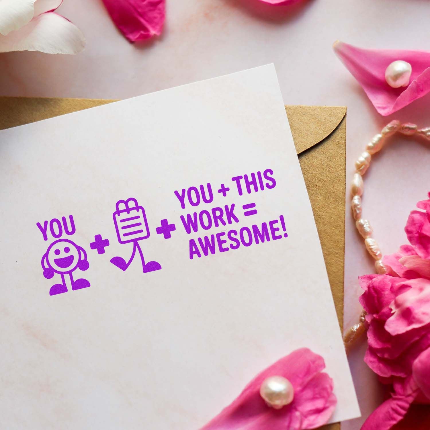 White card with a purple custom stamp reading You + This Work = Awesome, beside a brown envelope, pink petals, and pearls.