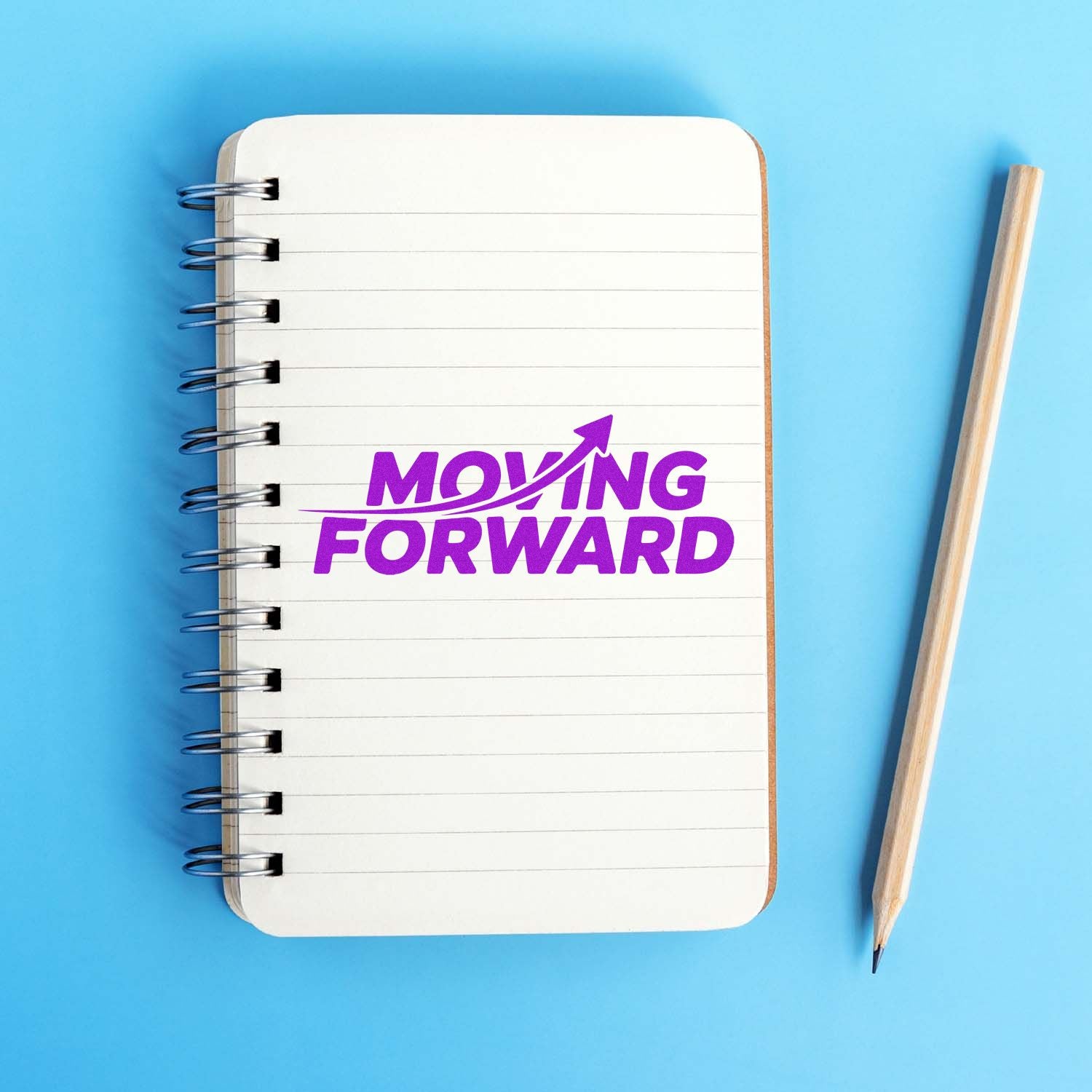 Purple Moving Forward stamp seal on lined spiral notebook, with pencil on blue background.