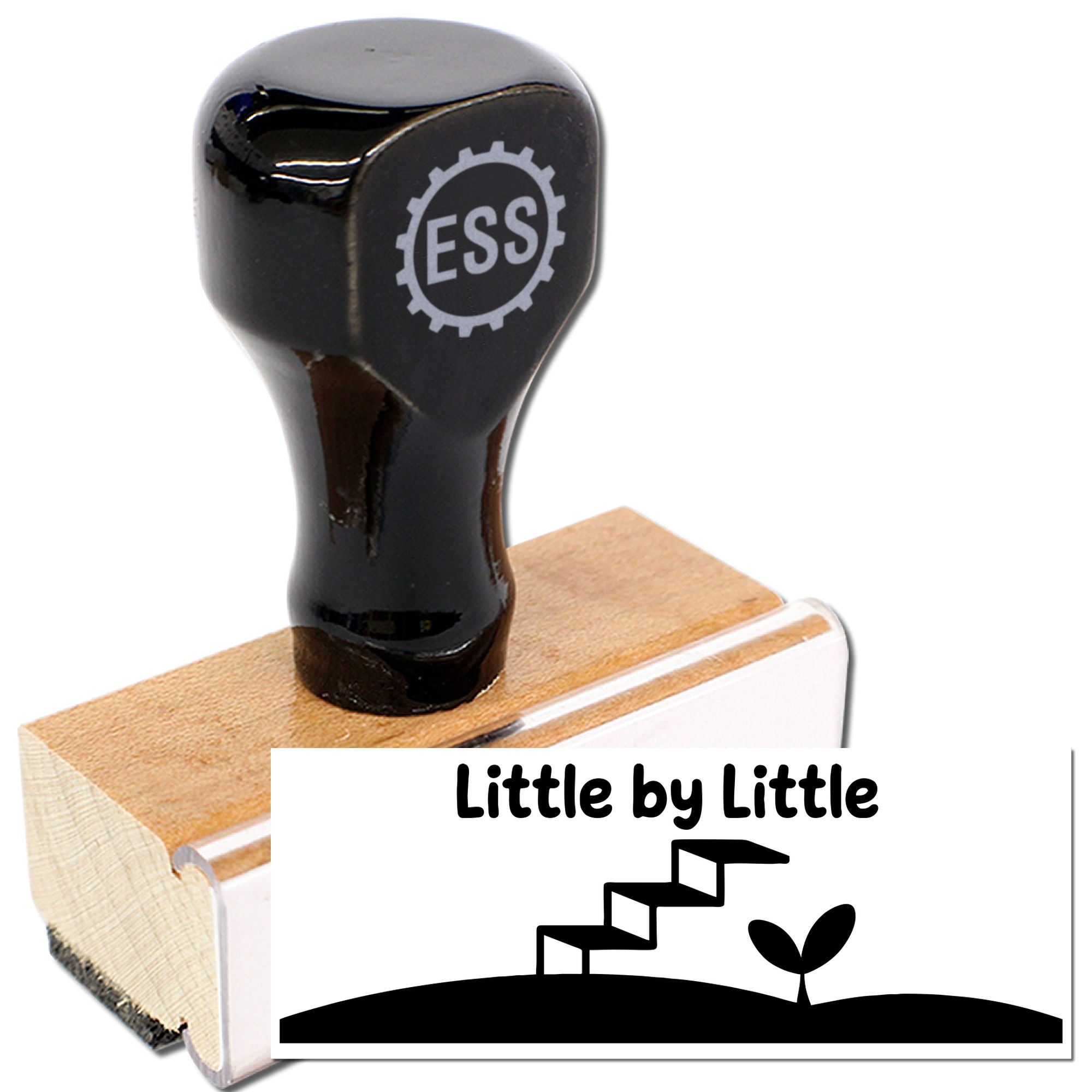 Black rubber stamp and seal on a wooden block, showing ESS logo and a white impression reading Little by Little.