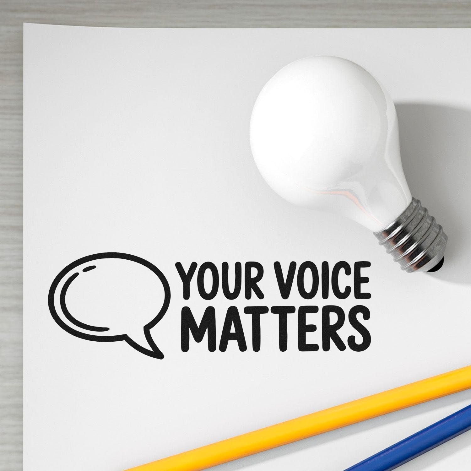 Custom stamp and seal design with white lightbulb, black Your Voice Matters text, speech bubble icon, and yellow and blue pencils.
