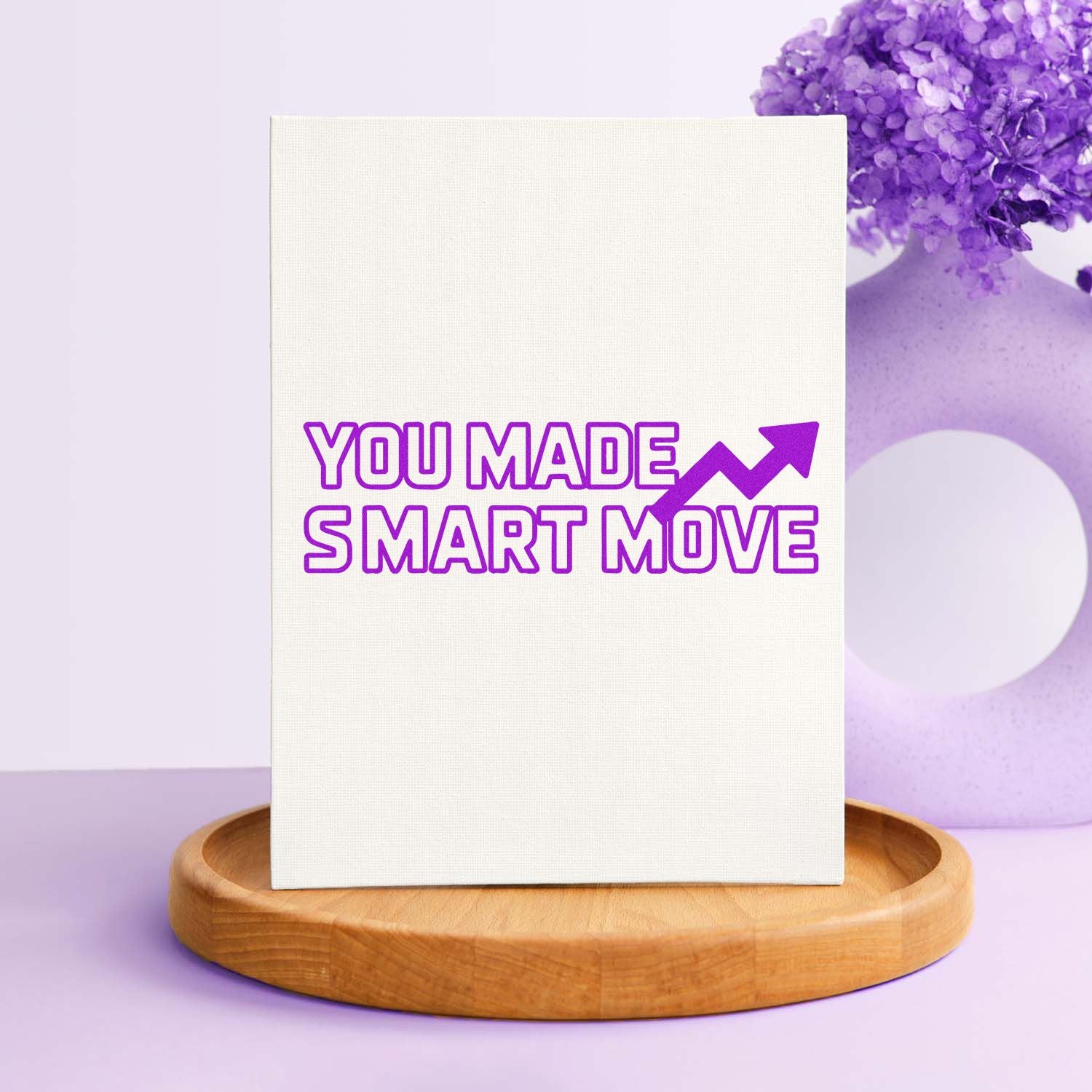 Purple custom stamp seal reading YOU MADE SMART MOVE with upward arrow on a white canvas display and wooden base.