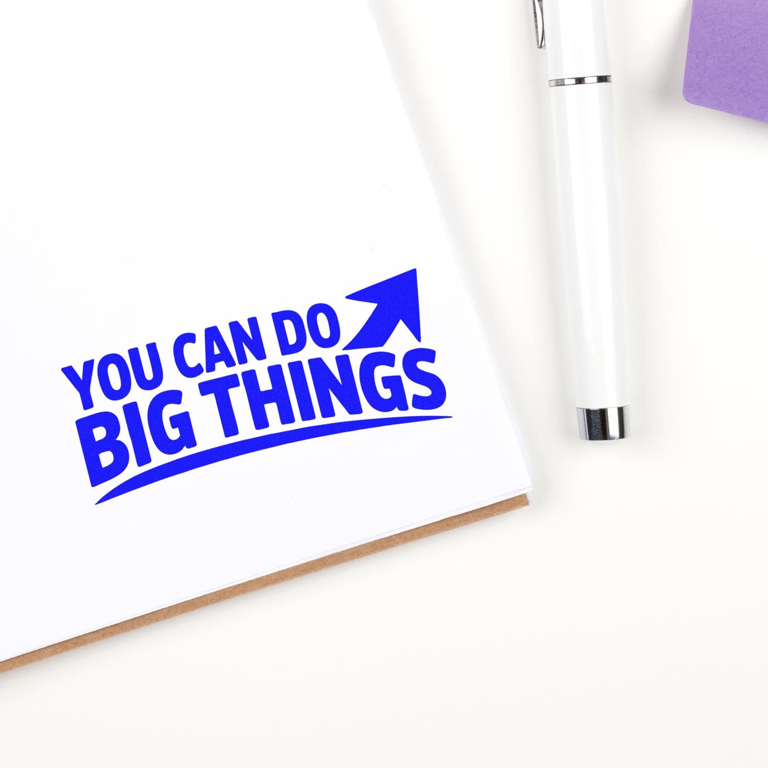 Blue custom stamp and white seal pen on white paper, reading You can do big things with an upward arrow.