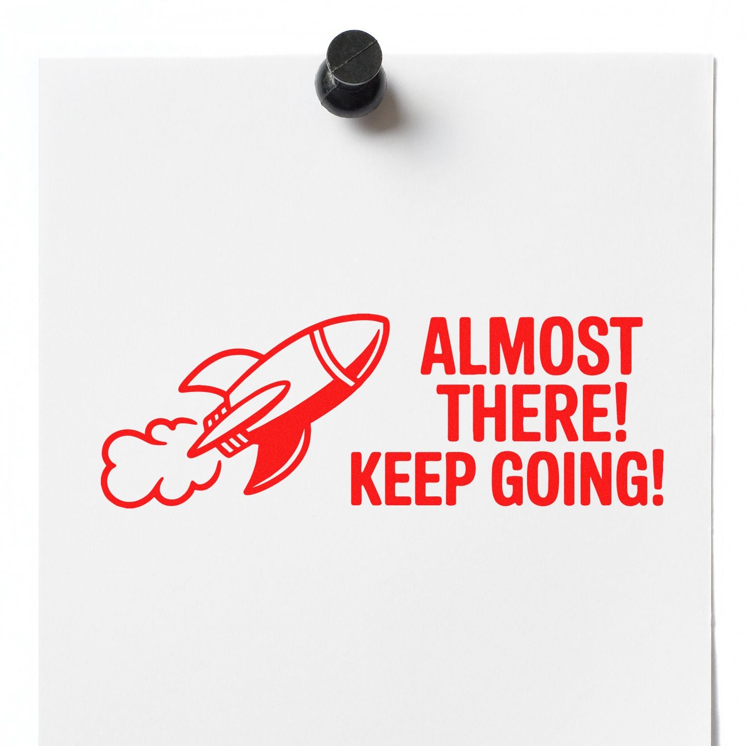 Red motivational stamp with rocket and ALMOST THERE! KEEP GOING! on white paper, topped by a black seal.
