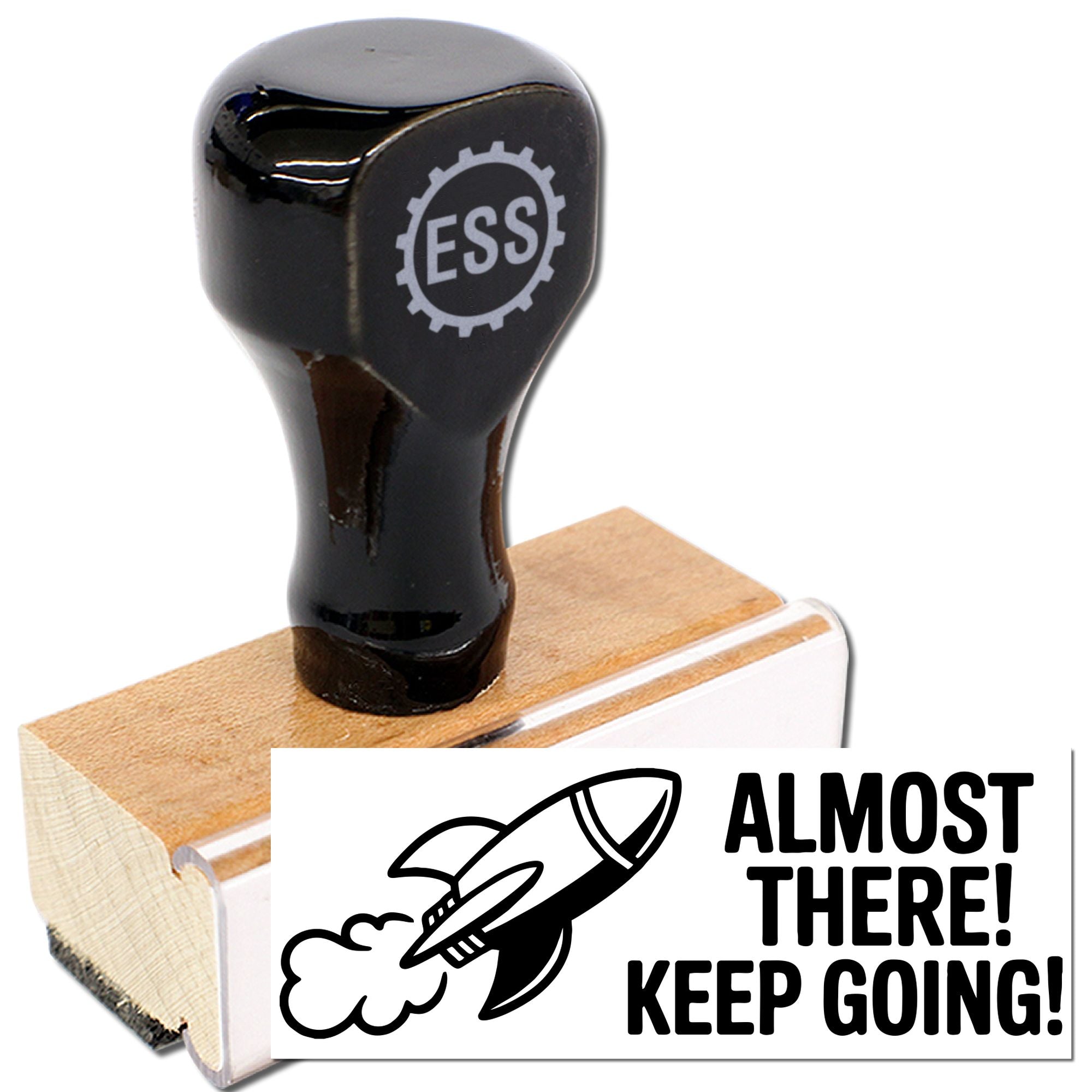 Black rubber stamp and seal on wooden base with ALMOST THERE! KEEP GOING! and a rocket icon.