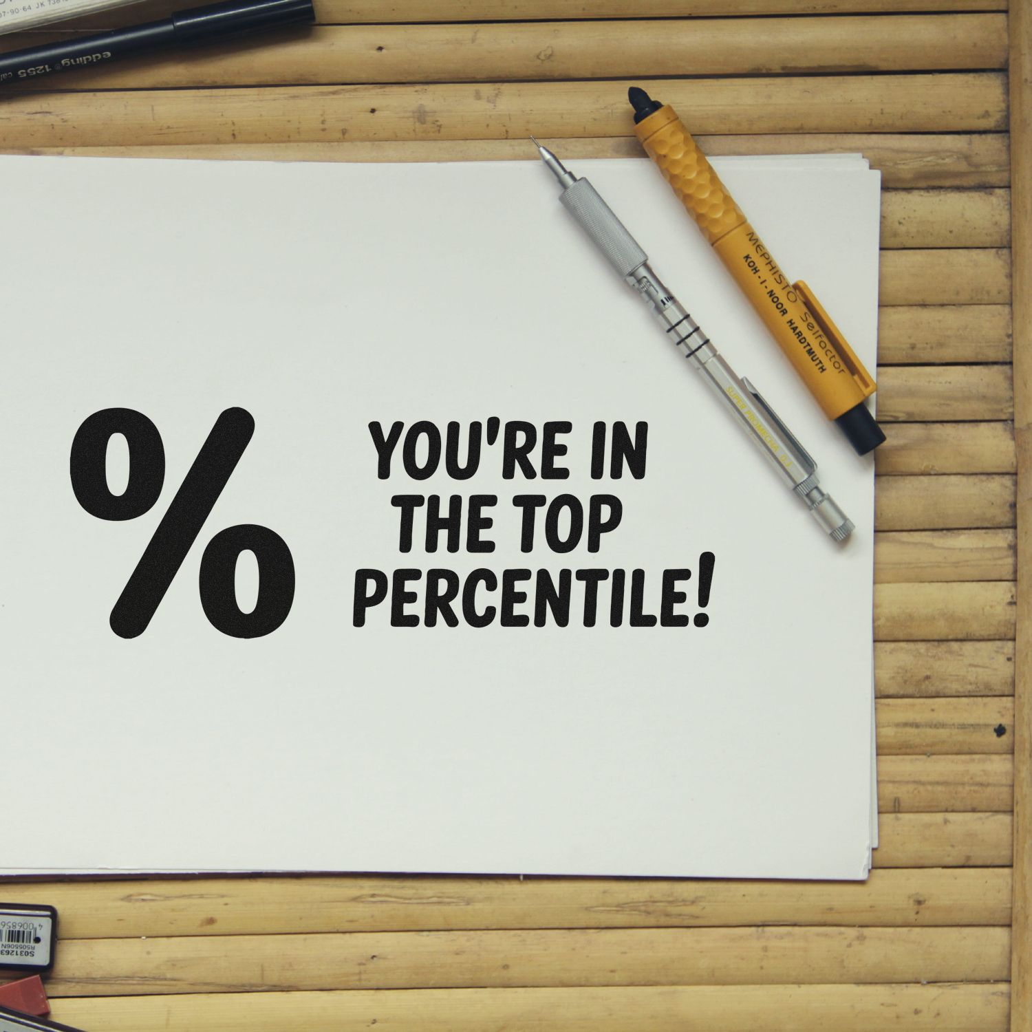 White stamp and seal products on wood desk with black Youre in the top percentile! text and gold markers.