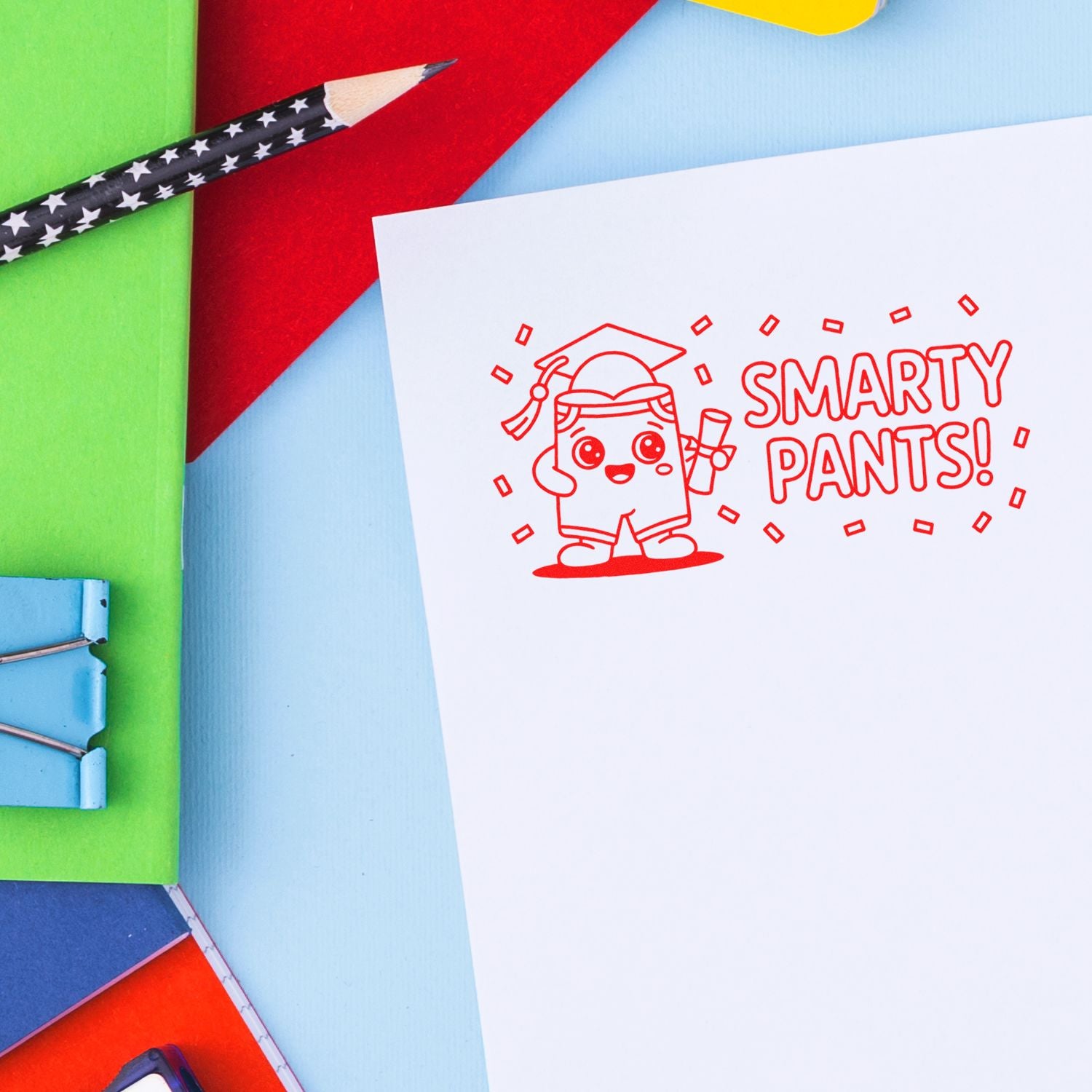 Red Smarty Pants! graduate rubber stamp on white paper, with colorful stationery, pencil, and binder clips.