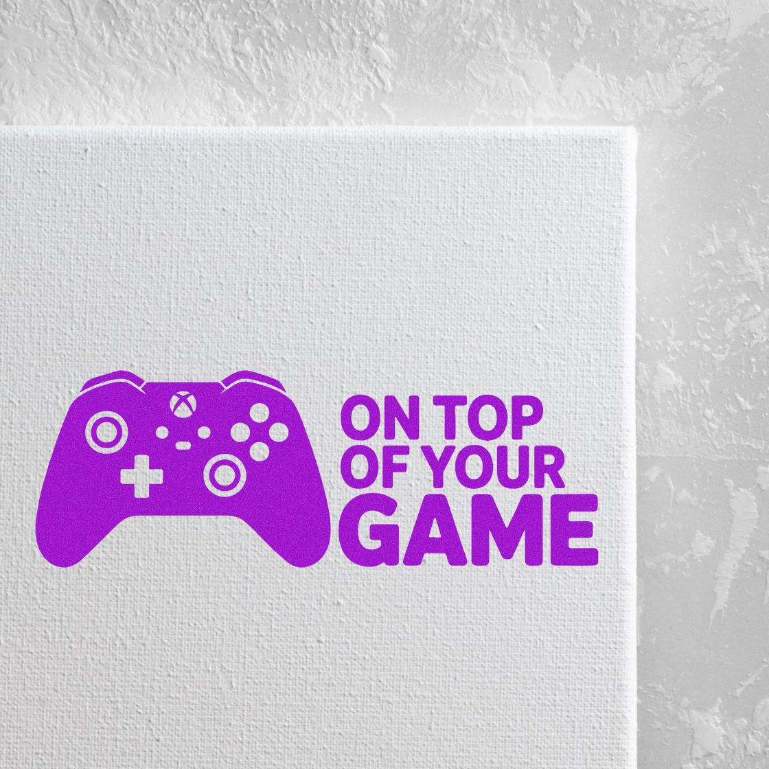 Purple game controller stamp and seal with ON TOP OF YOUR GAME text on white textured canvas.