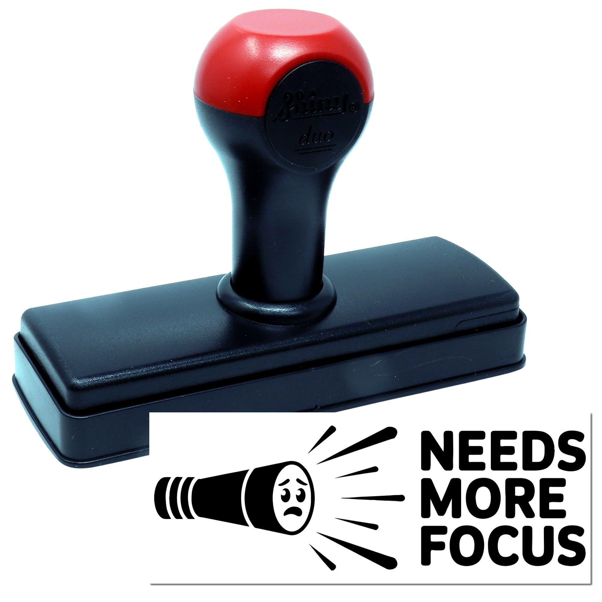 Red-and-black self-inking seal stamp with black base and Needs More Focus graphic on a white background.