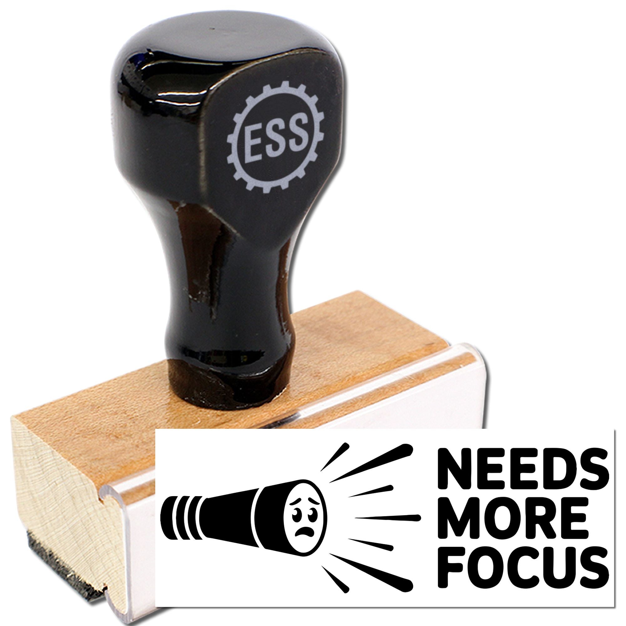 Black ESS rubber stamp and seal on wooden base with white NEEDS MORE FOCUS label and flashlight icon