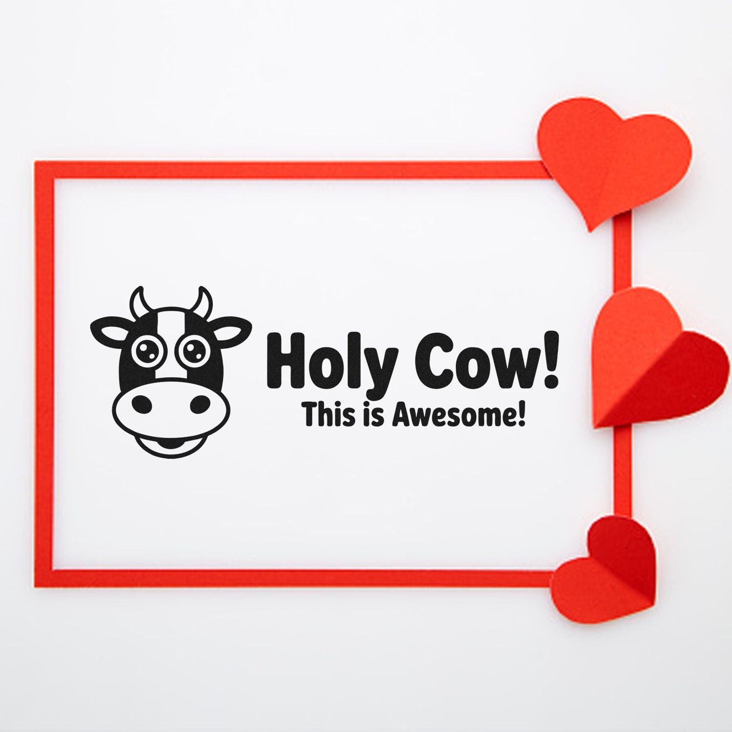 Black cow stamp reading Holy Cow! This is Awesome! with a red border and red heart seal accents on white background.