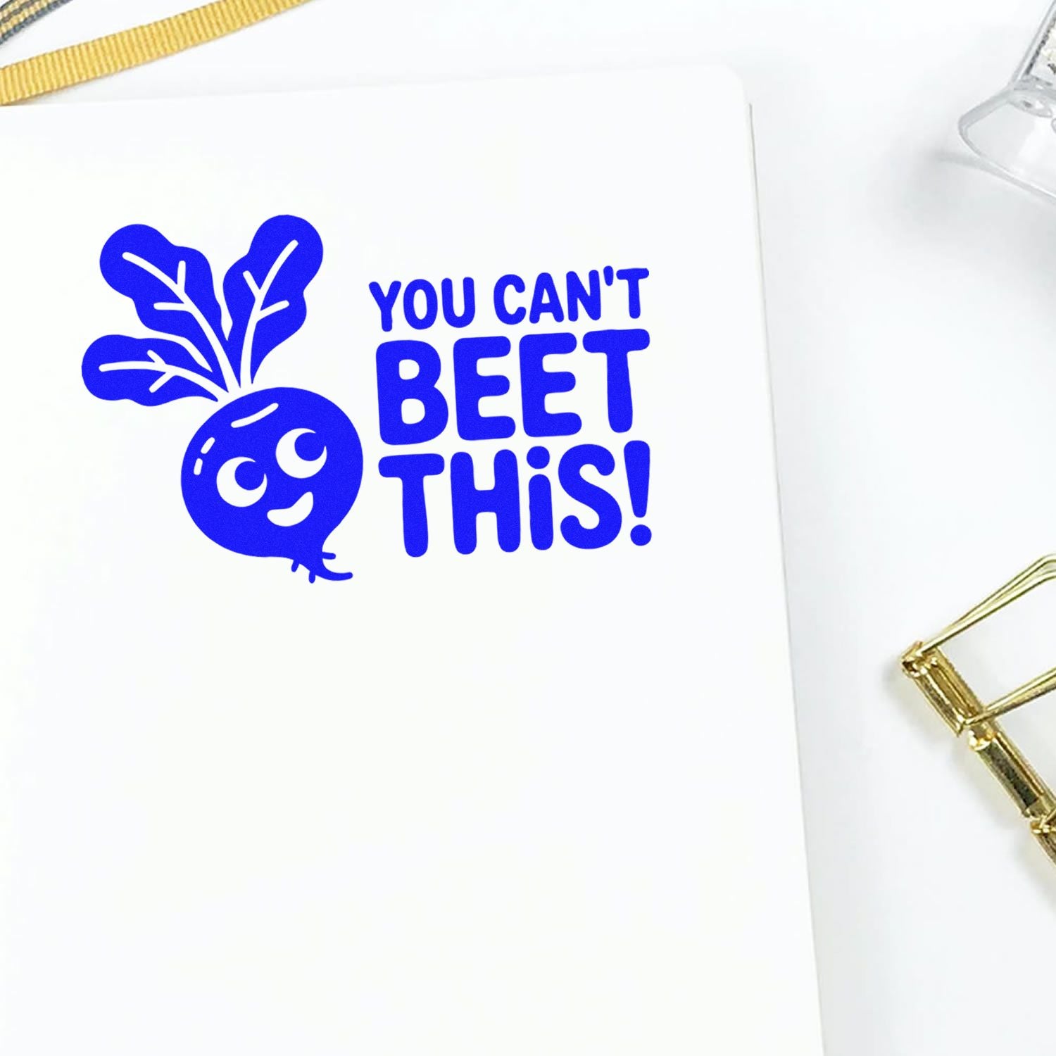 Blue custom stamp and seal reading You cant beet this! with smiling beet graphic on white paper, gold clip and ribbon.