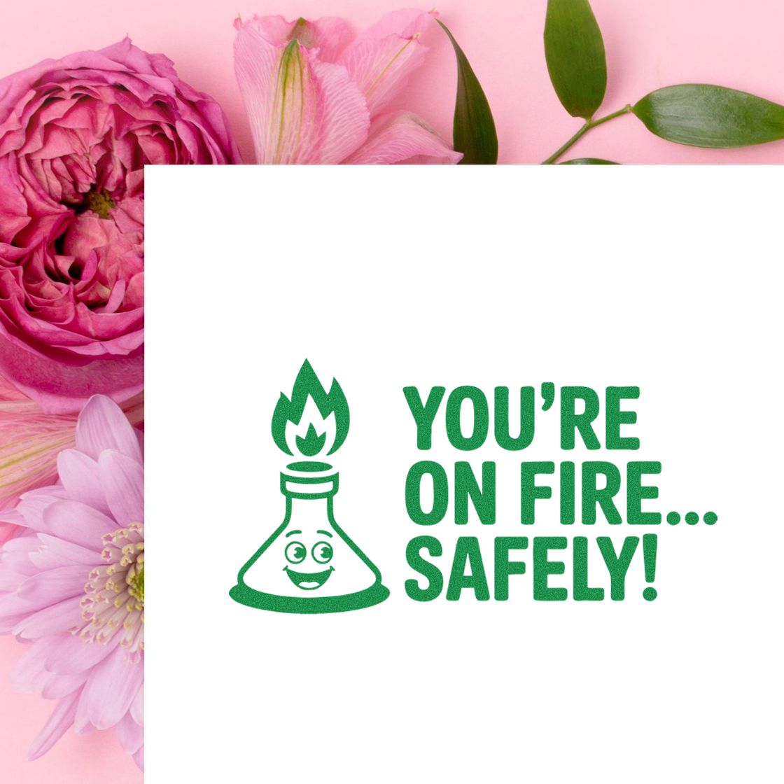 Green stamp seal with smiling flaming flask and Youre on fire... safely! on a pink floral background.