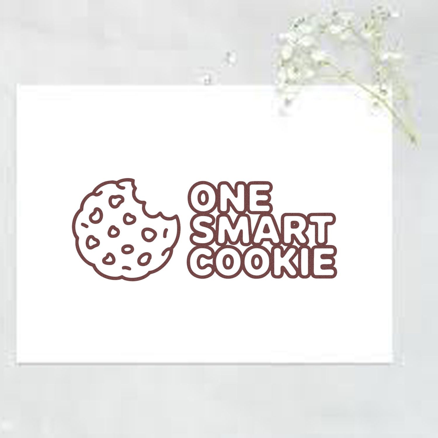 Brown One Smart Cookie stamp and seal with cookie icon on white card, accented by delicate white flowers.