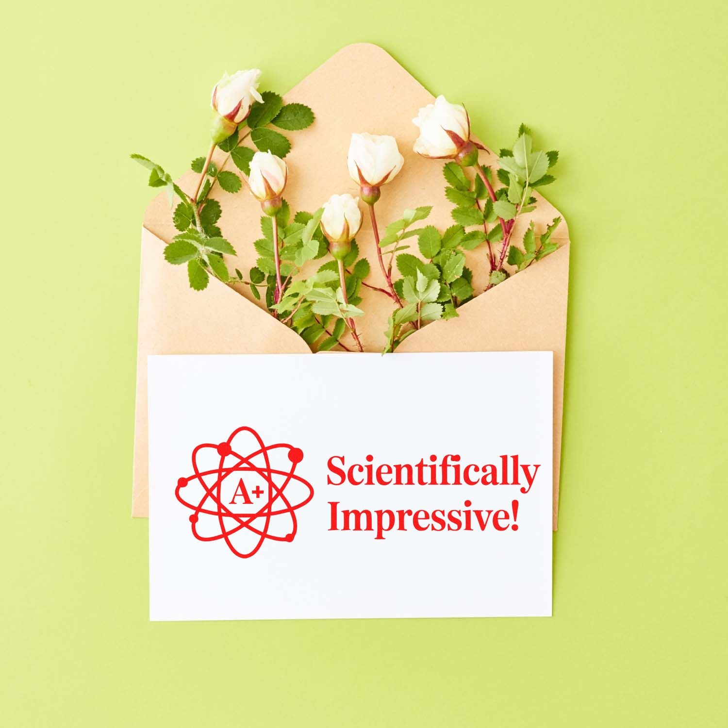 Red A+ stamp seal reading Scientifically Impressive! on a white card, with roses in a tan envelope on light green.