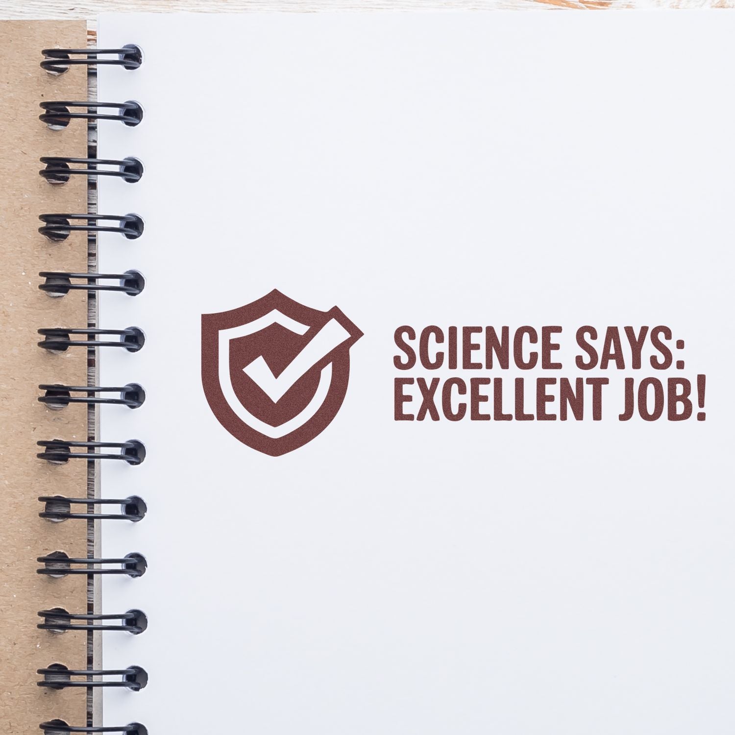 Brown stamp and seal with shield checkmark and Science Says: Excellent Job! on a white spiral notebook page.