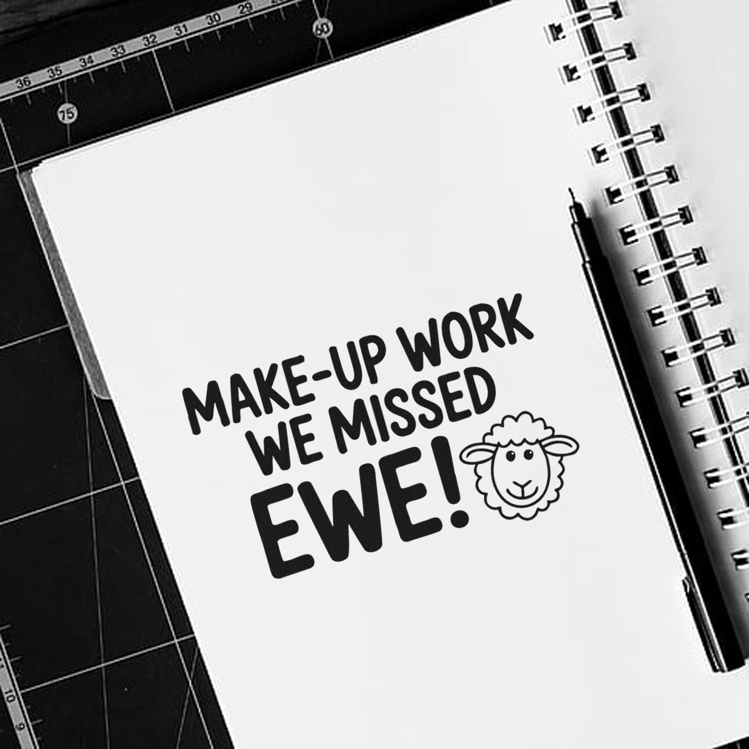 Black-and-white stamp design on spiral notebook reads Make-up work we missed Ewe! with a sheep icon.