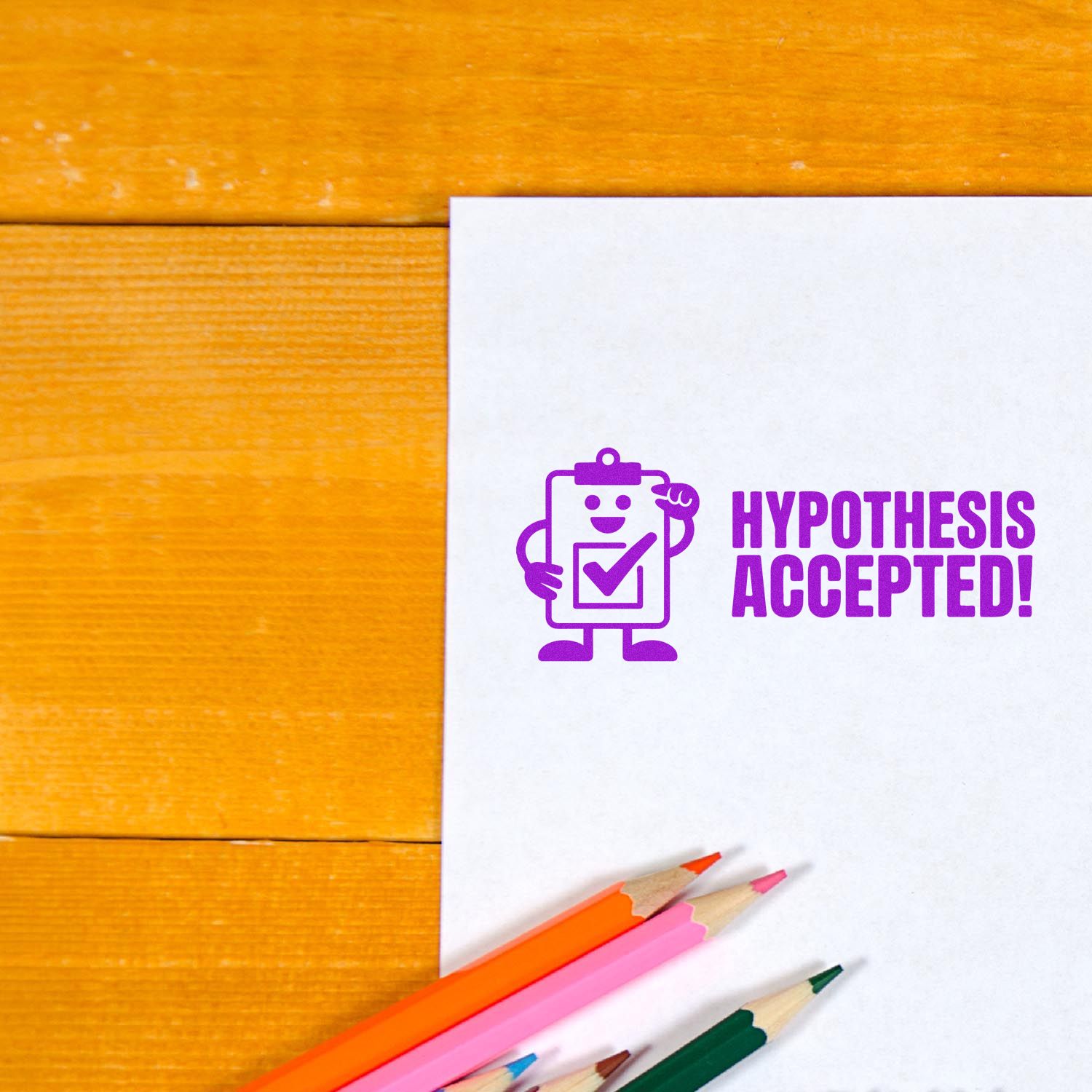Purple Hypothesis Accepted! stamp seal on white paper with colored pencils on an orange wood desk.