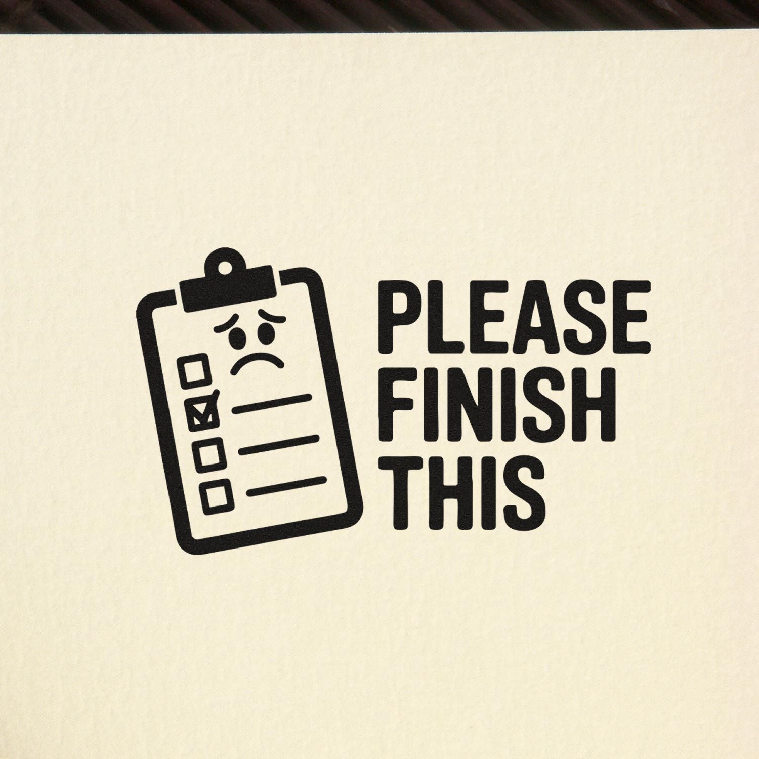 Black stamp-style clipboard with sad checklist and Please Finish This text on cream fabric background.
