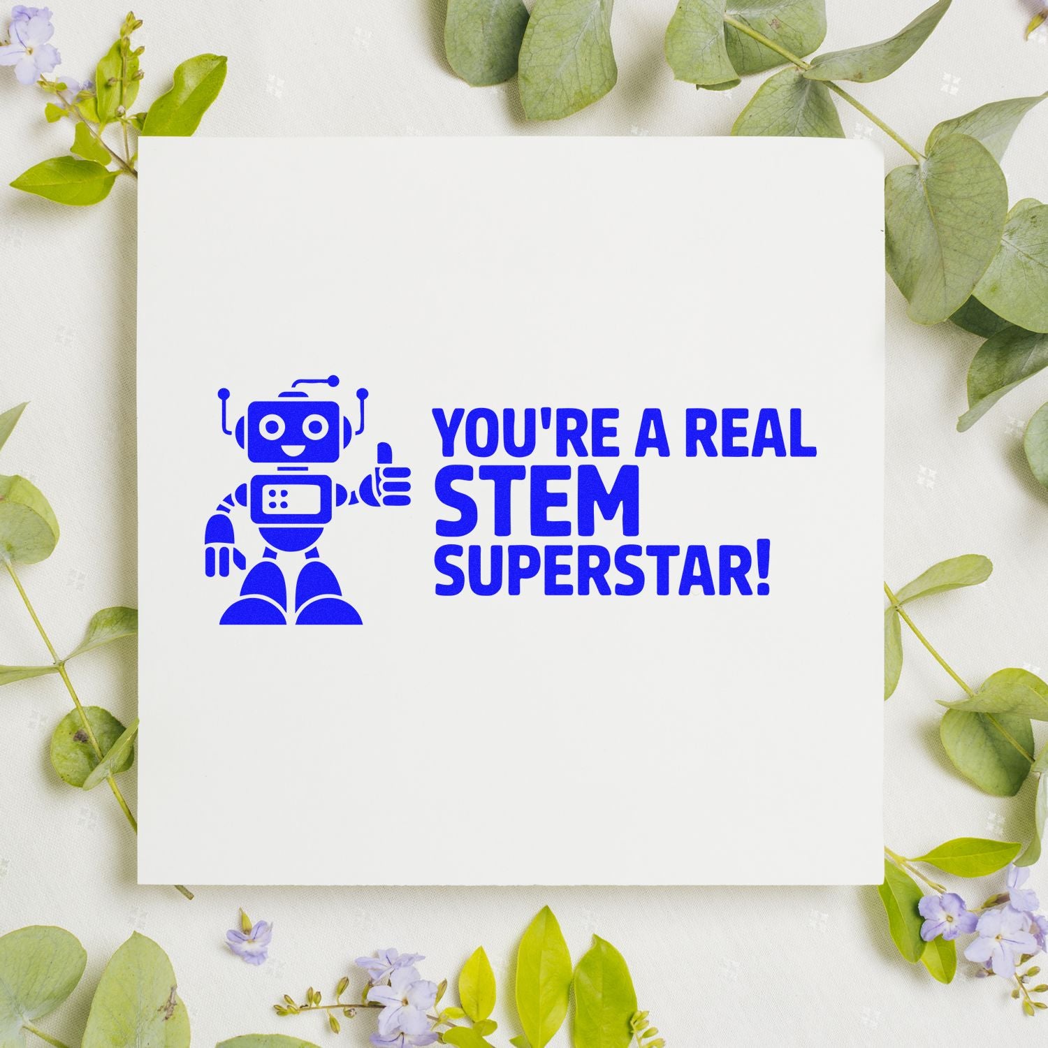 Blue STEM Superstar stamp seal with robot on white card, surrounded by green leaves and purple flowers.