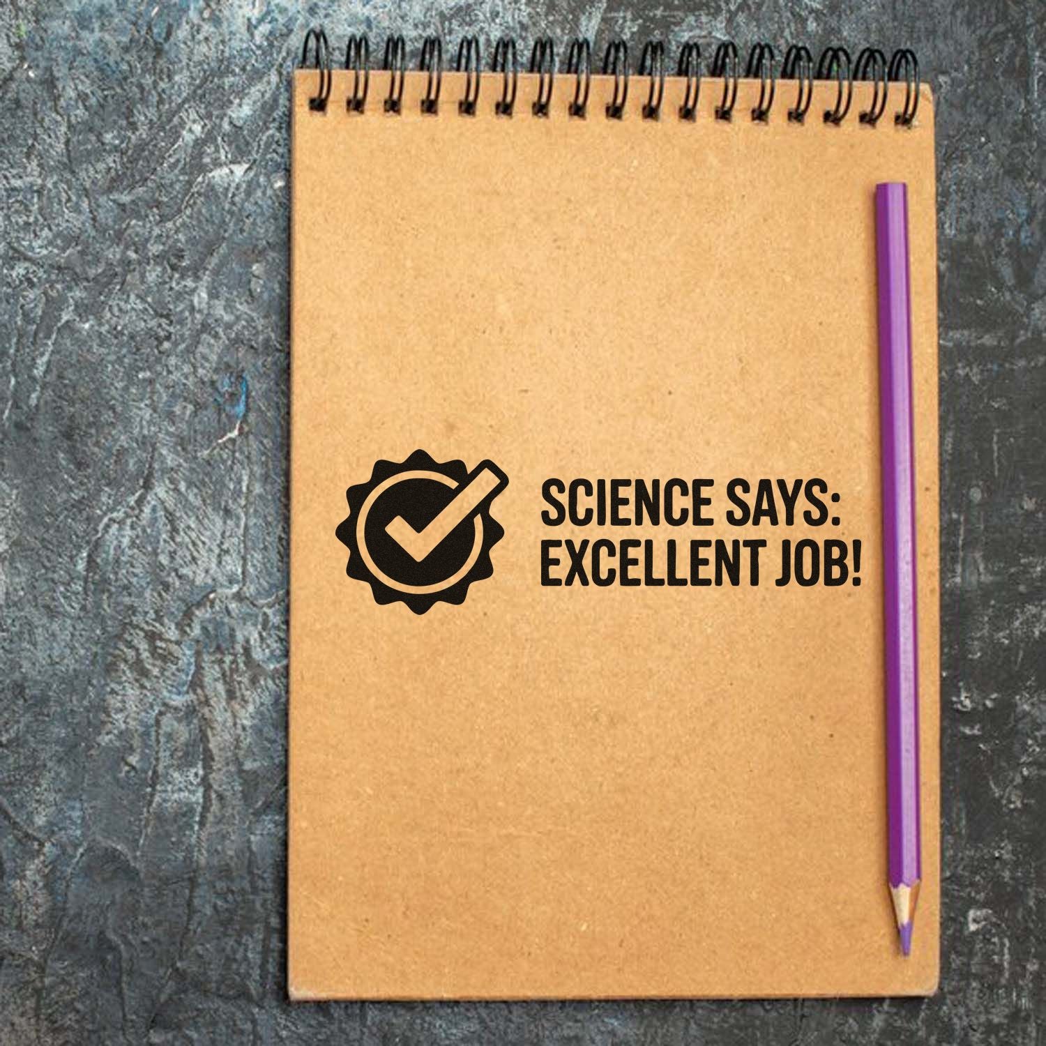 Kraft notebook with black science stamp and seal reading Science says: Excellent job! and a purple pencil.