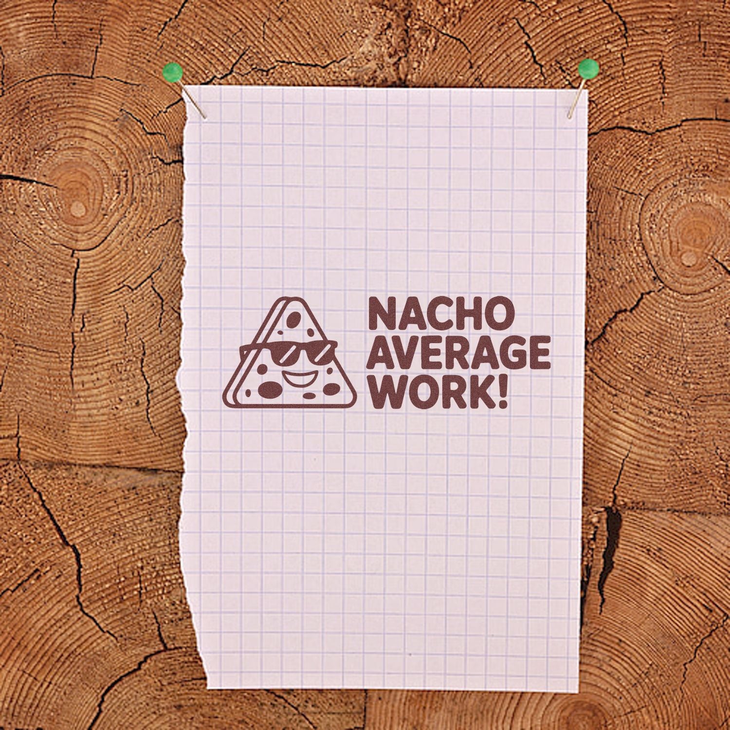 Brown custom rubber stamp design with nacho character and Nacho Average Work! on white graph paper, clipped to wood.