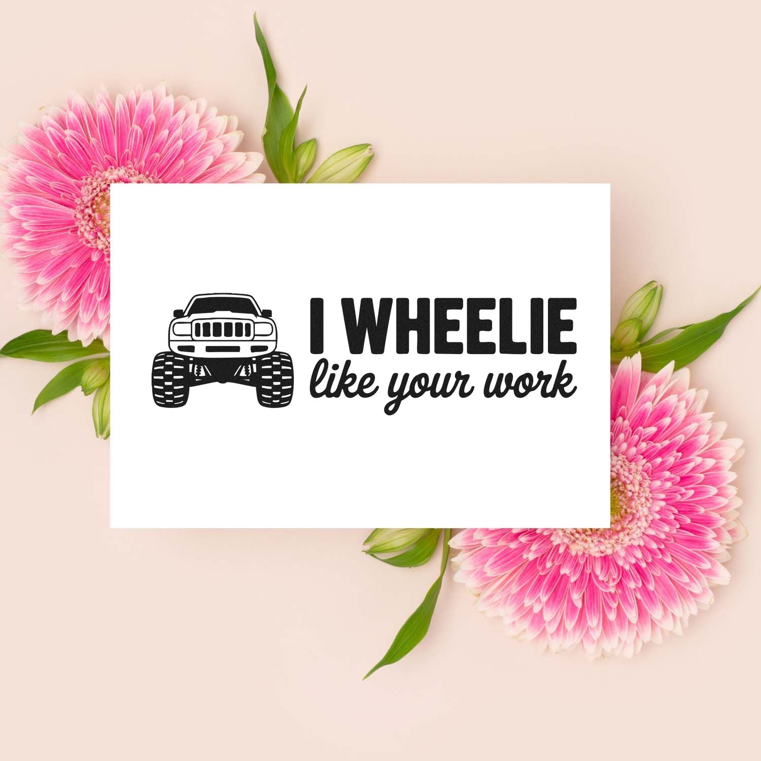 Black truck rubber stamp with I wheelie like your work on white card, framed by pink gerbera flowers on beige.