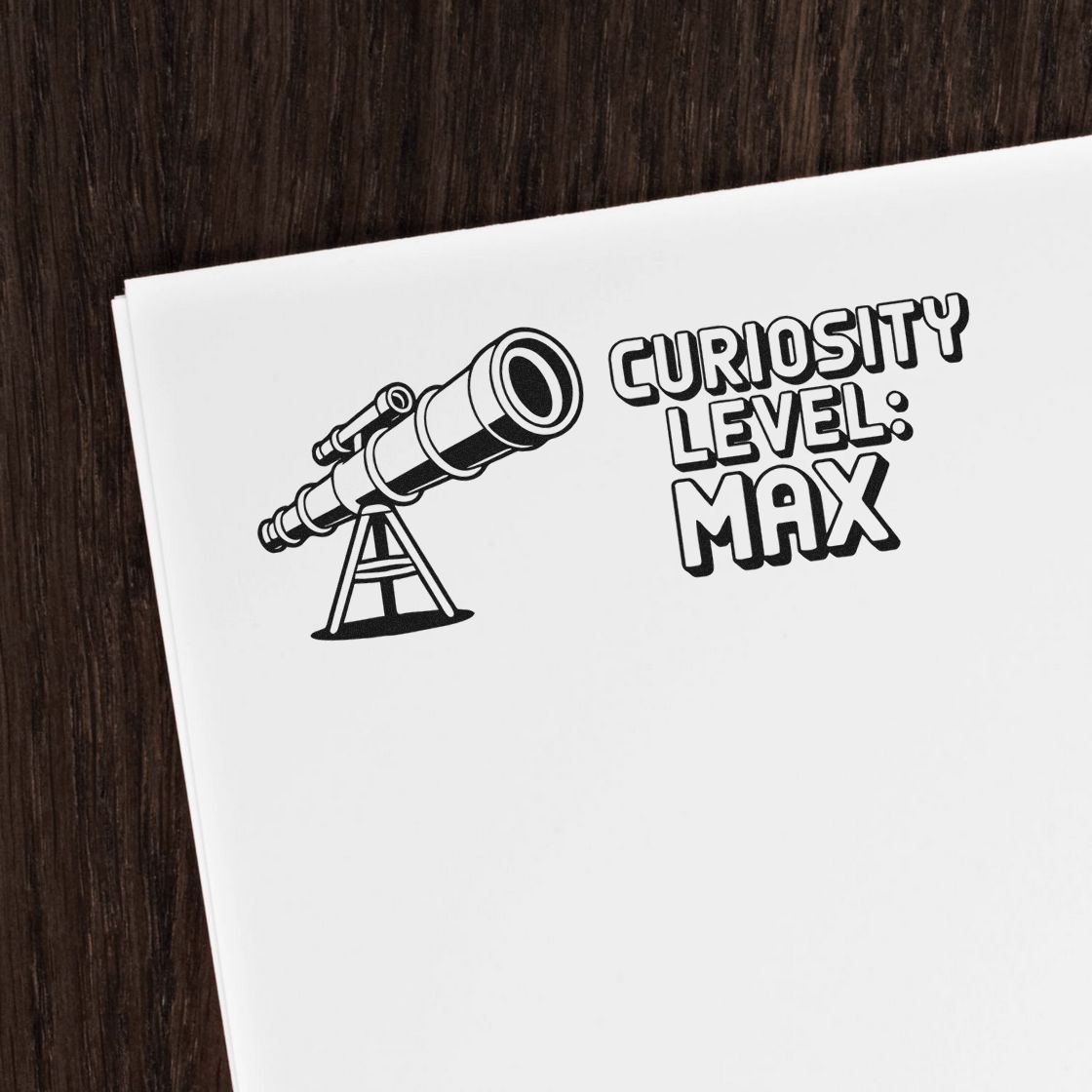 Black custom stamp and seal featuring a telescope and Curiosity Level: Max on white paper over dark wood background.