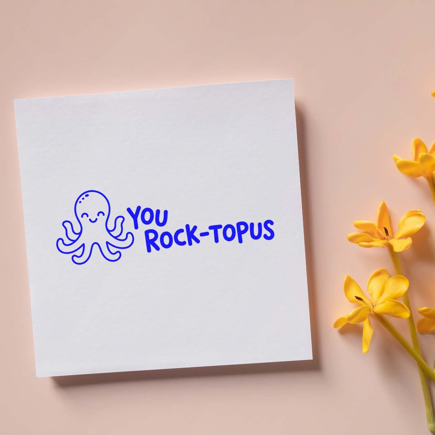 White stamp and seal card with blue octopus and YOU ROCK-TOPUS text, on blush pink background with yellow flowers.