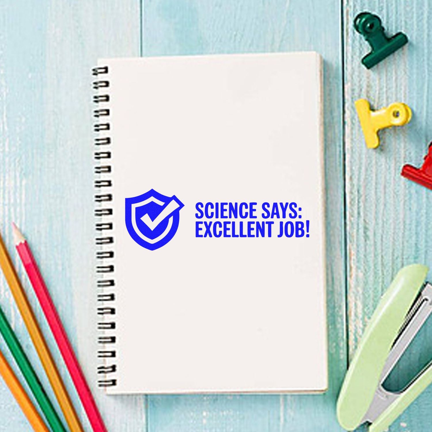 Blue stamp seal with shield check and Science Says: Excellent Job! on white notebook, with colorful stationery.
