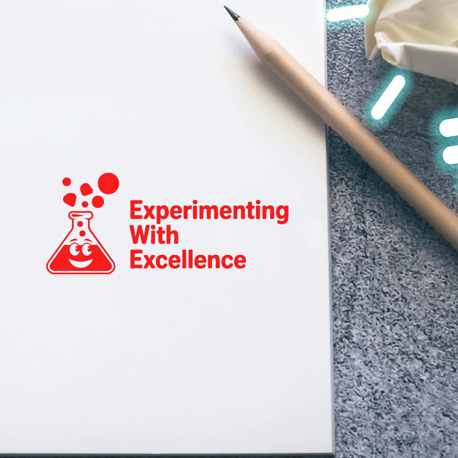 Red lab flask stamp seal reading Experimenting With Excellence on white paper, with pencil on gray background.