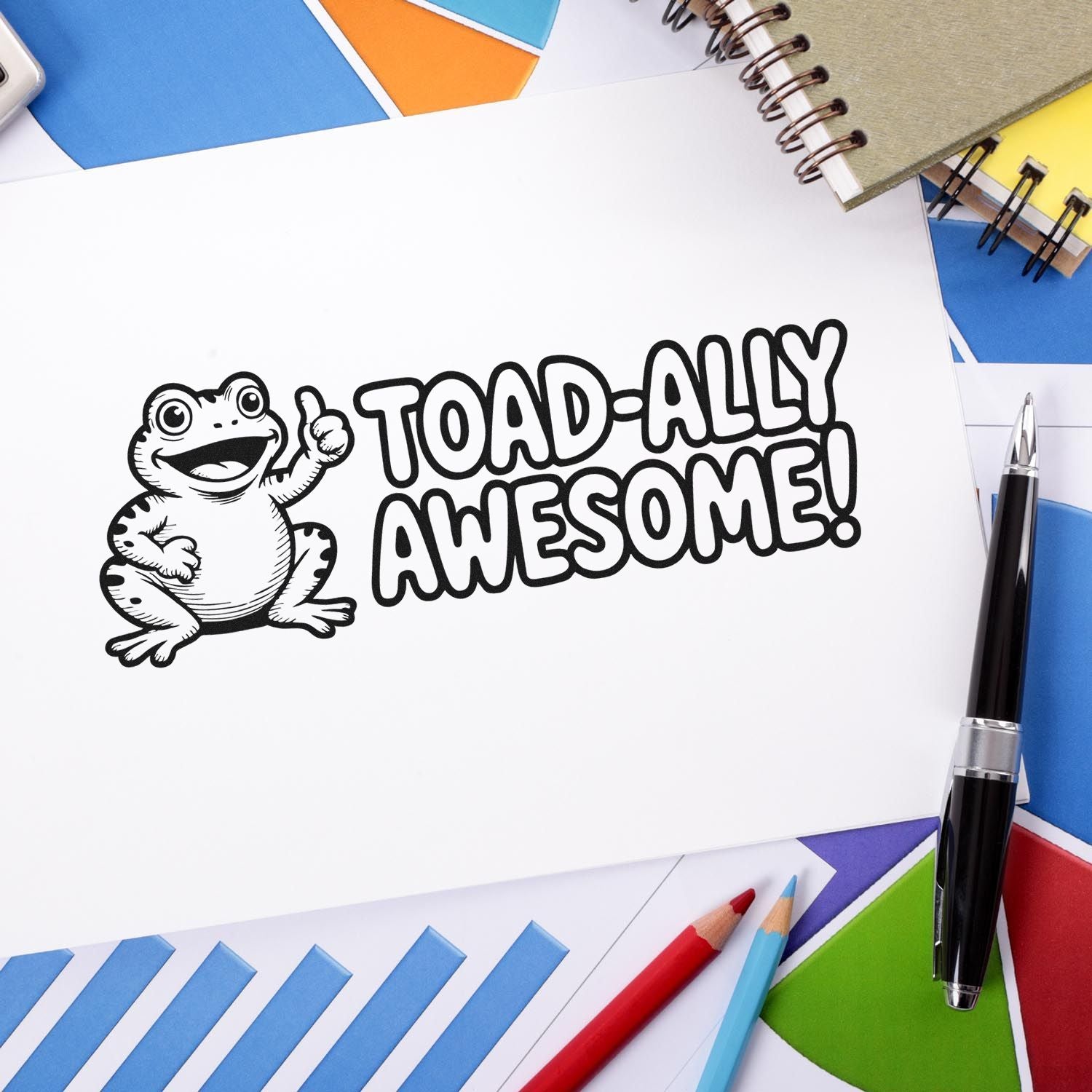 Black-and-white Toad-ally Awesome stamp on white paper, surrounded by colorful seal swatches, notebooks, and pens.