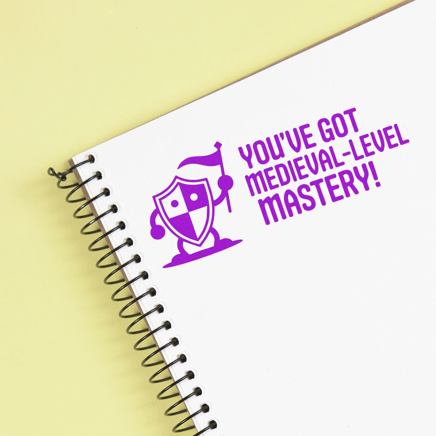 Purple medieval stamp seal on white spiral notebook with "You've got medieval-level mastery!" on pale yellow.