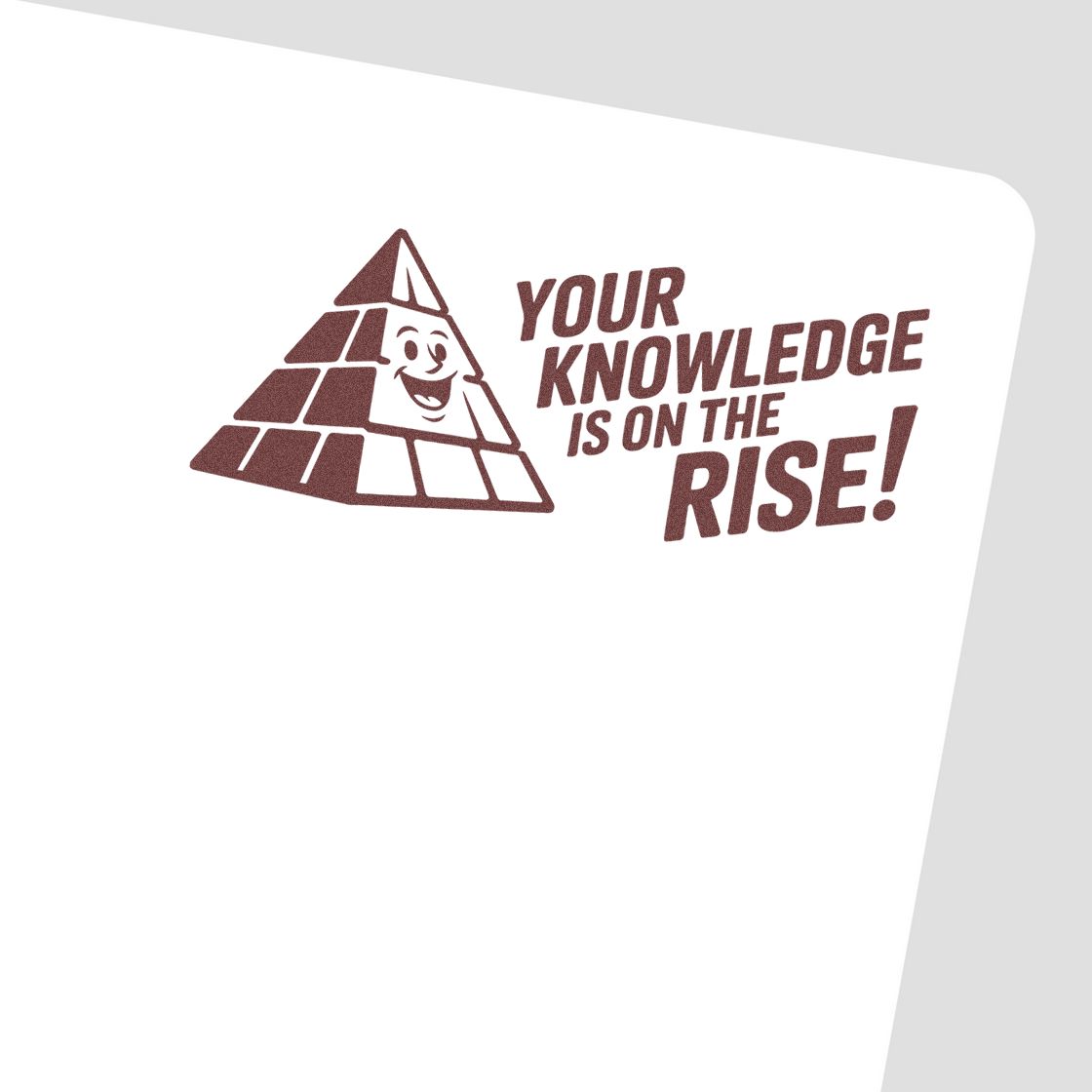Brown stamp seal featuring a smiling pyramid and the slogan Your knowledge is on the rise! on a white surface.