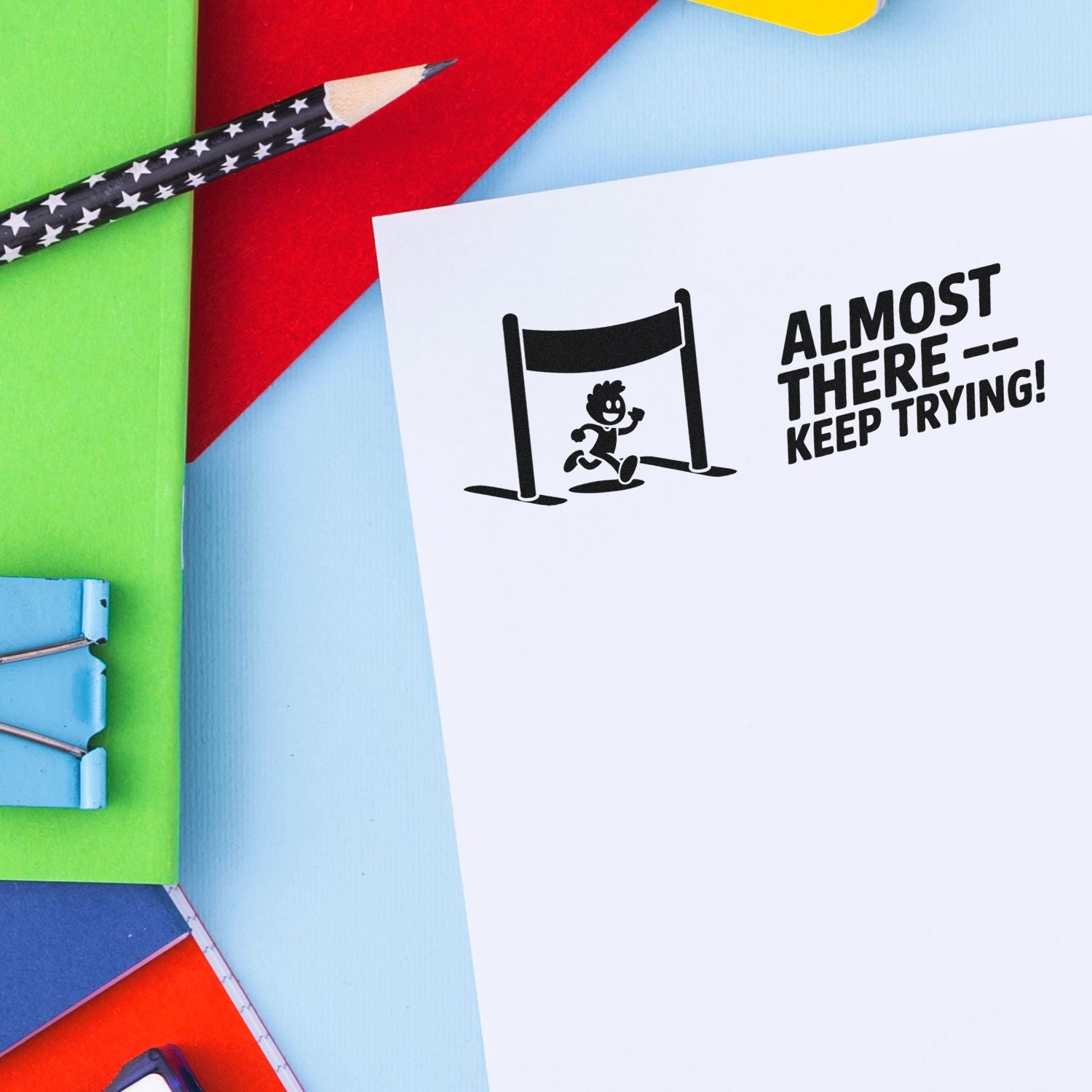 Black motivational stamp on white paper: runner over hurdle with ALMOST THERE  KEEP TRYING! on bright multicolor backdrop.