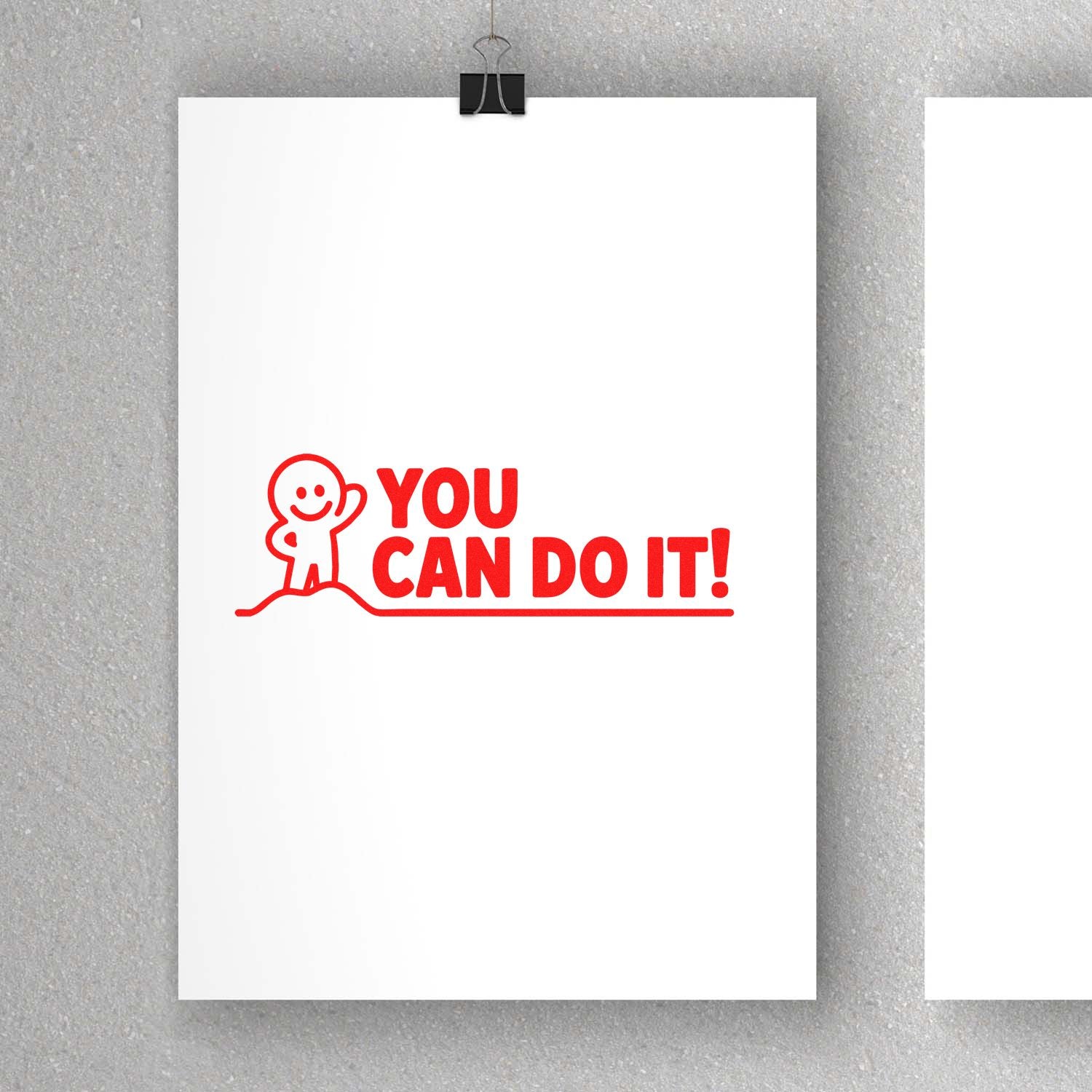 Red rubber stamp seal with smiling figure and YOU CAN DO IT! on white paper against a gray background.