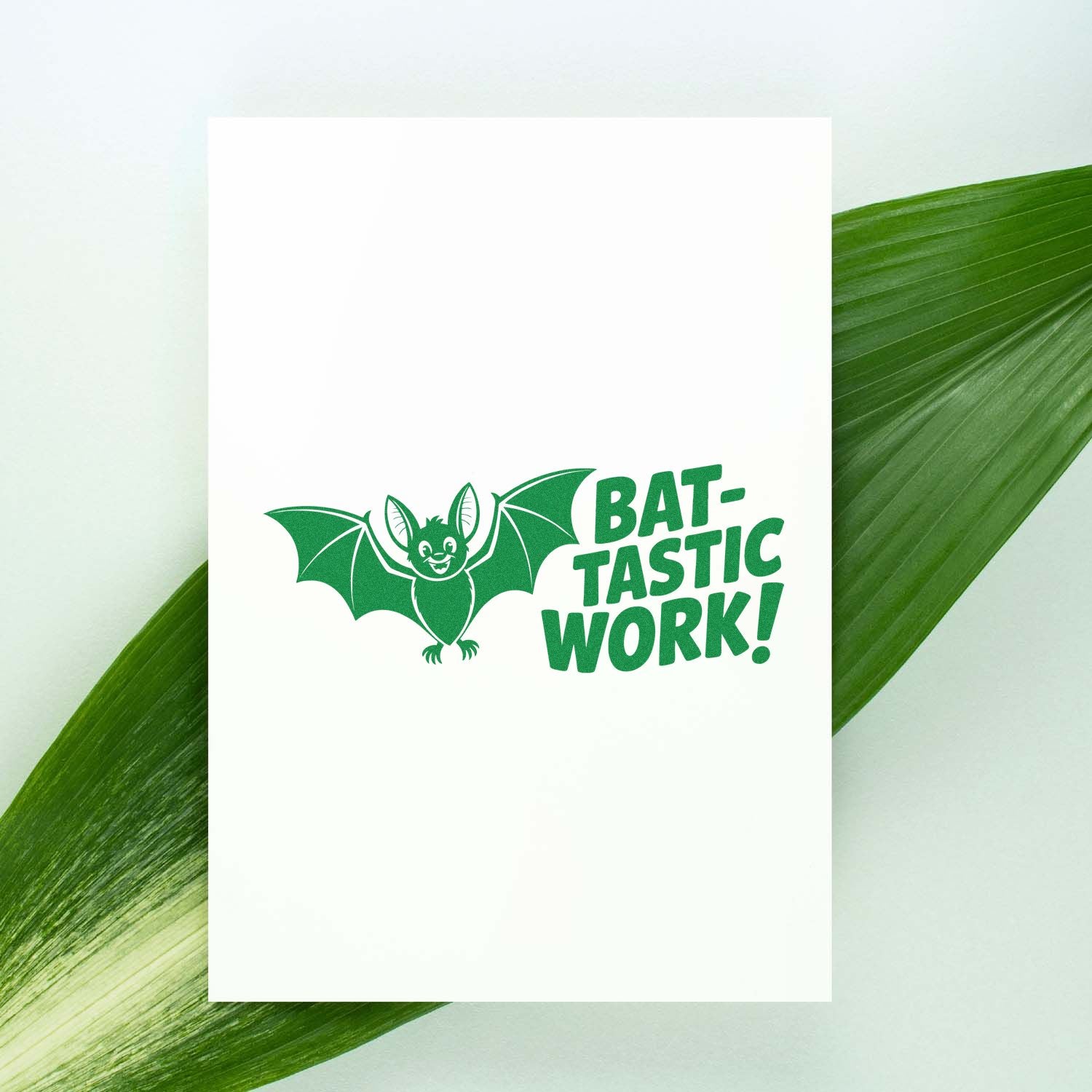 Green custom stamp seal with bat graphic and BAT-TASTIC WORK! on a white card over leaf background.