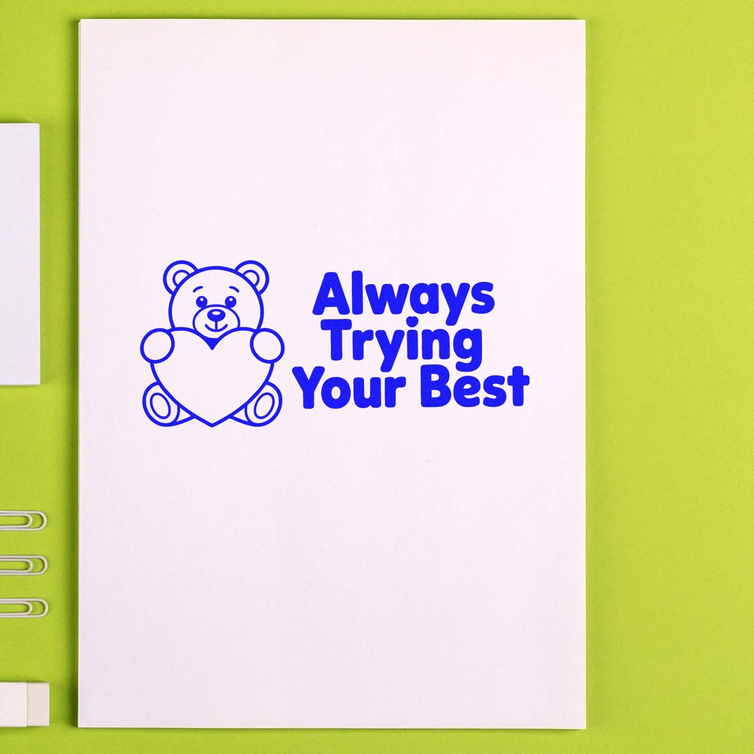 Blue custom stamp seal with teddy bear holding a heart and Always Trying Your Best on white paper, lime green background.