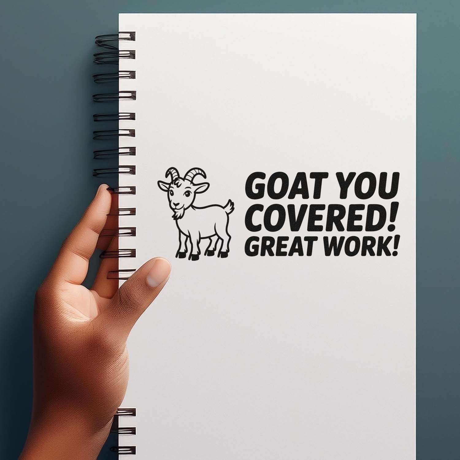 Black goat stamp and seal on a white notebook cover, reading GOAT YOU COVERED! GREAT WORK! on a teal background.