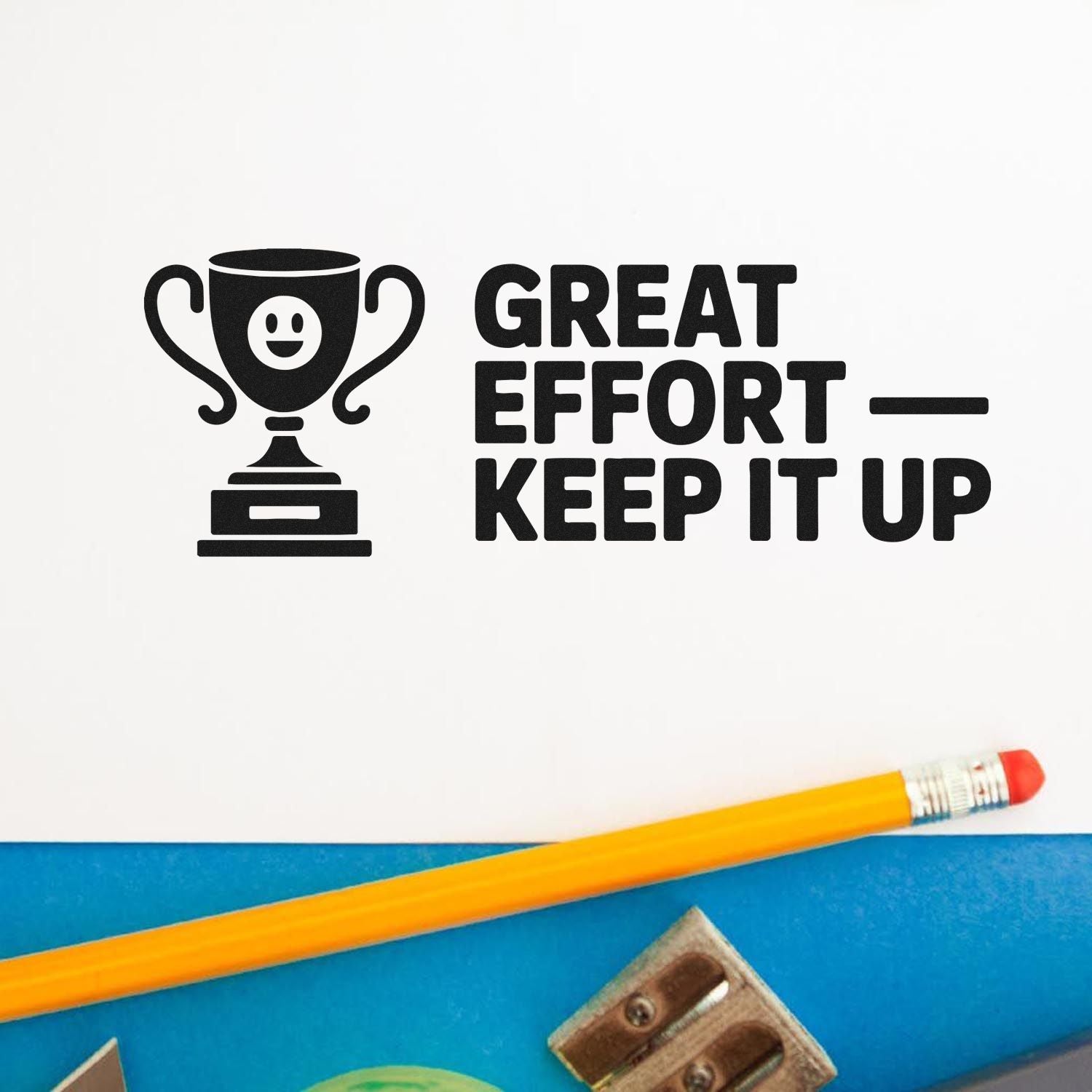 Black trophy stamp seal reading Great Effort  Keep It Up on white, with yellow pencil on blue background.