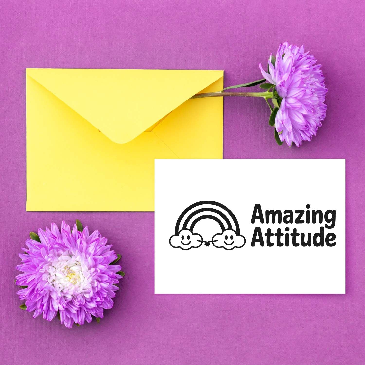 Yellow envelope on purple background with purple flowers and a white card featuring an Amazing Attitude rainbow stamp seal.