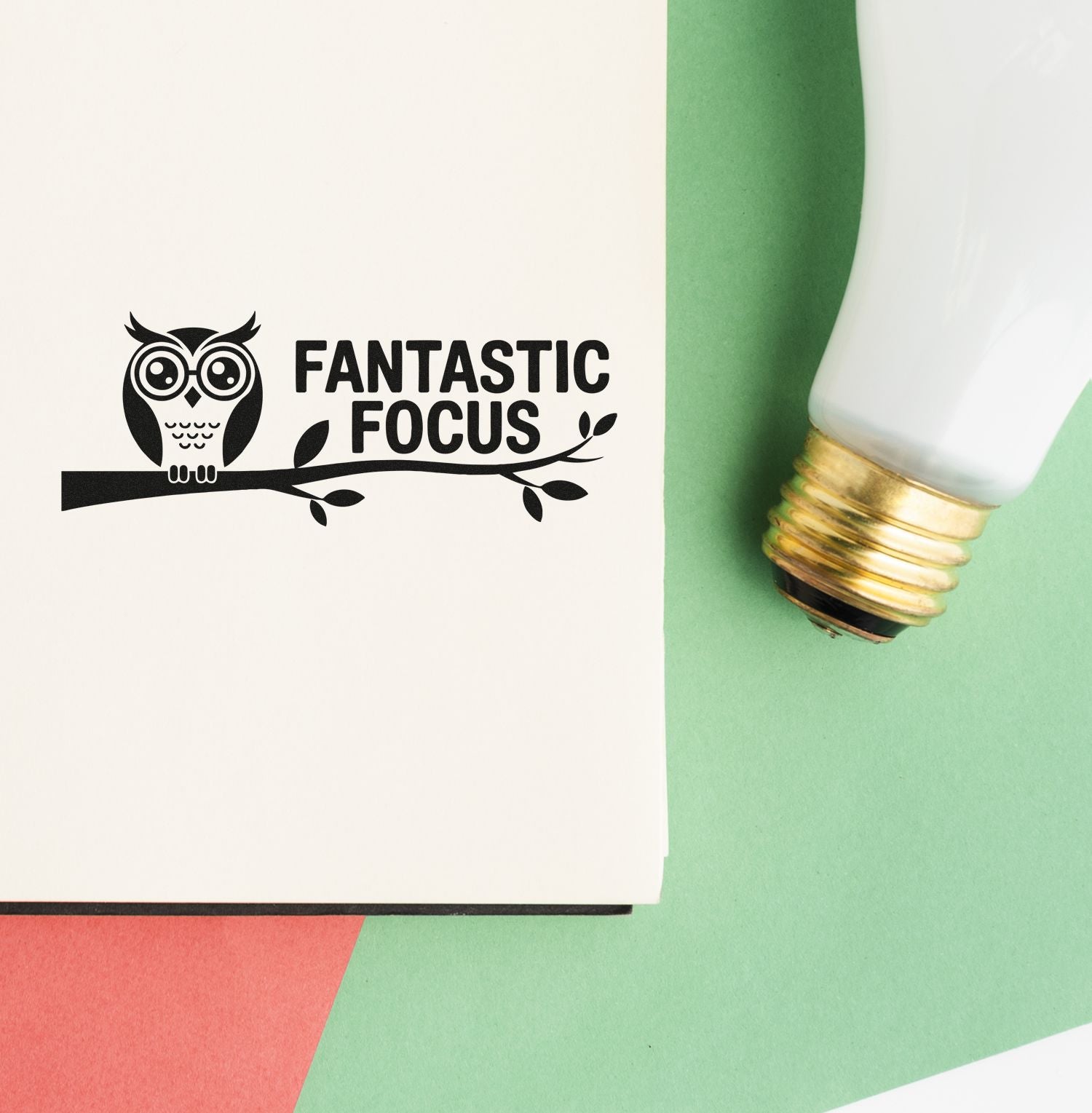 Black owl logo stamp reading Fantastic Focus beside a white-and-gold seal applicator on cream and green paper.