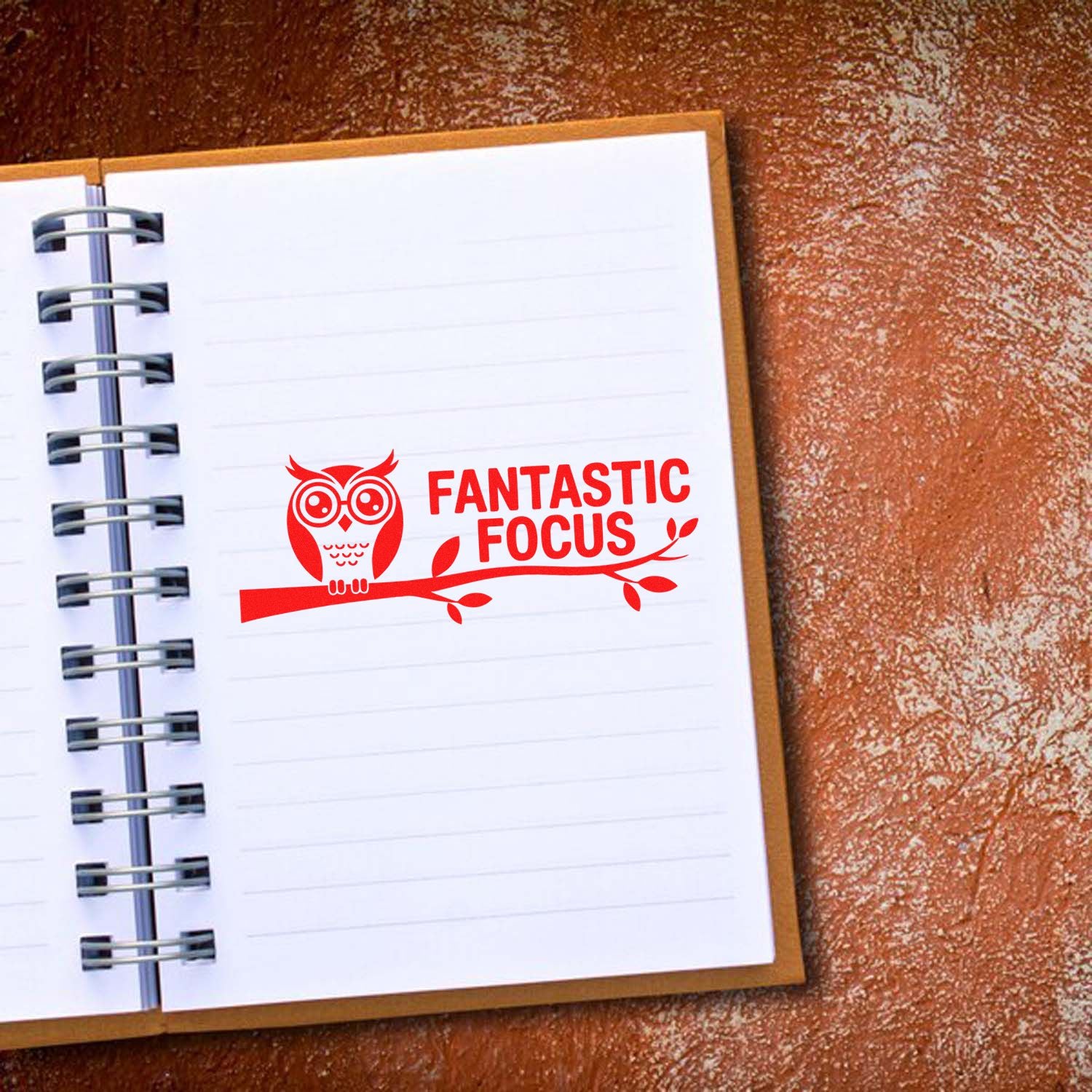 Red owl stamp seal reading Fantastic Focus on a white spiral notebook page with brown cover.