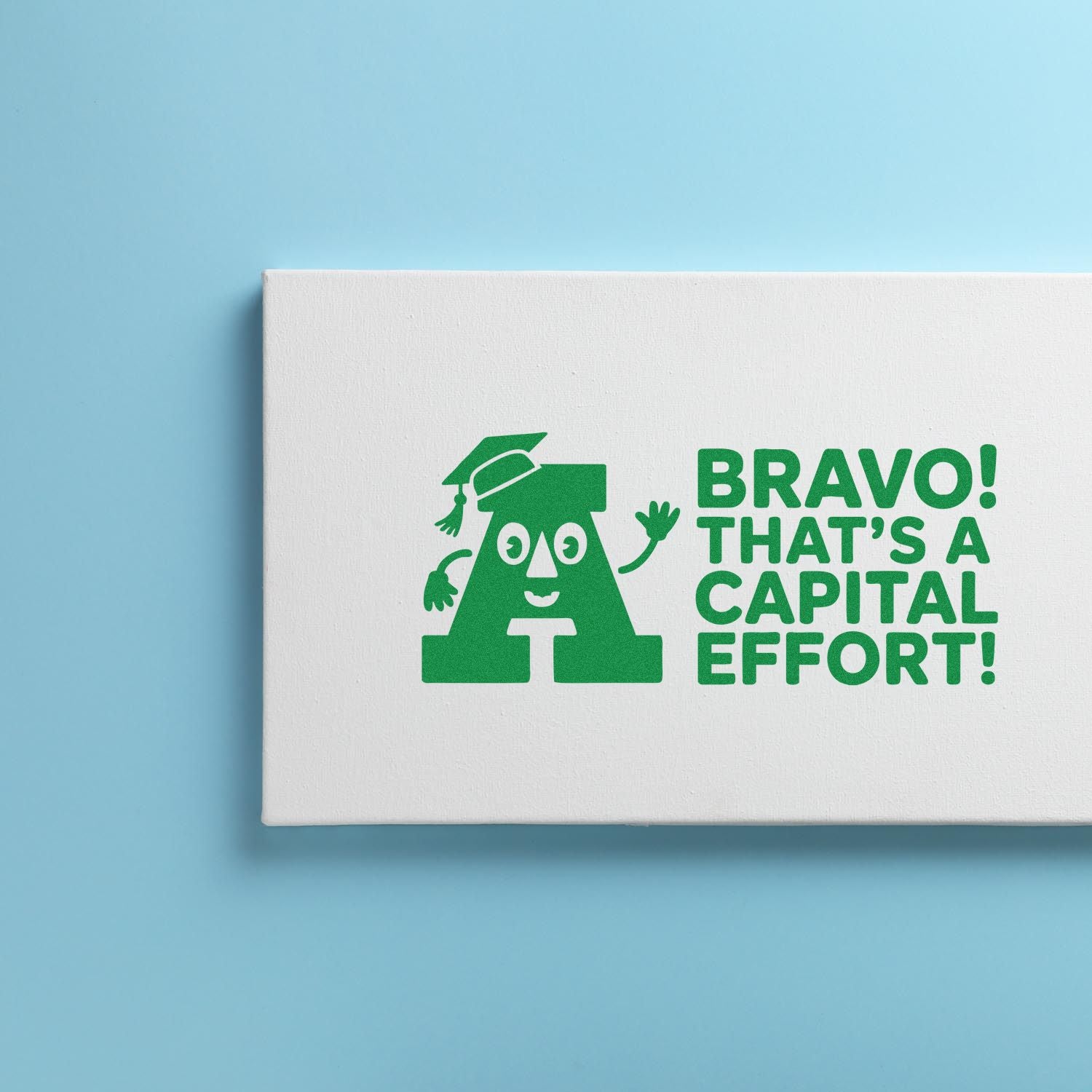 White stamp and seal block on blue background with green Bravo! Thats a capital effort! and a graduation-cap letter A.