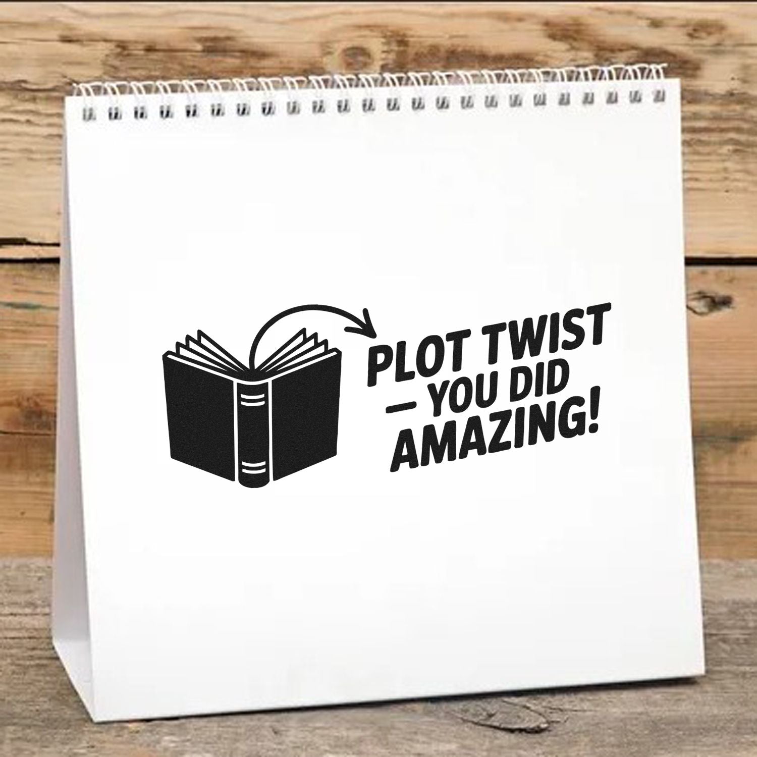 White spiral-bound stamp and seal display with black book icon and Plot twistyou did amazing! text on a wood background.