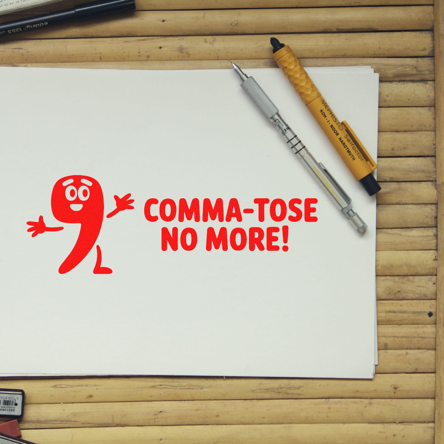 Red Comma-tose No More! stamp and seal products on white paper, with silver and yellow tools on a wood desk.