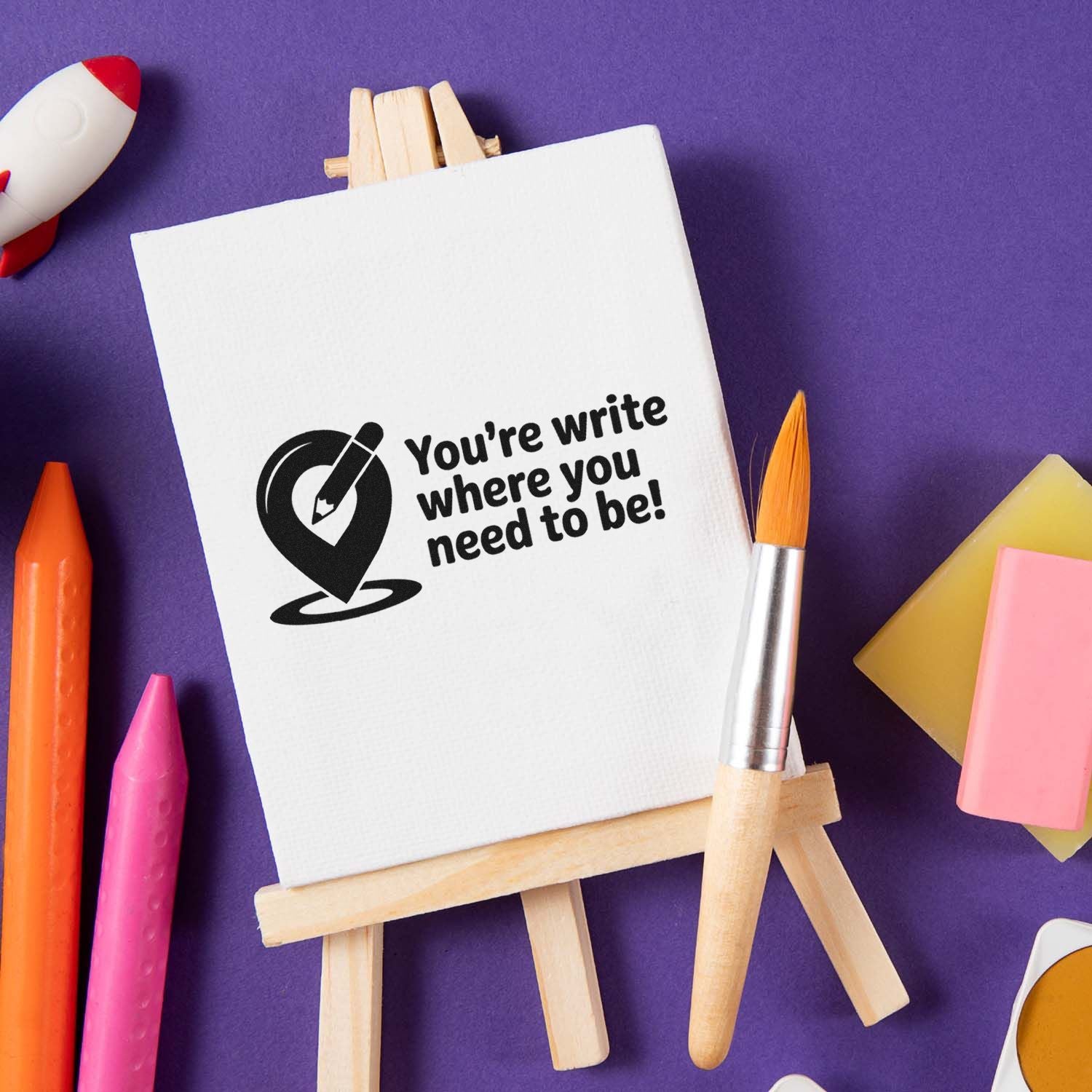 Custom stamp and seal on white canvas easel with black writing logo, surrounded by colorful pens and a paintbrush on purple background.