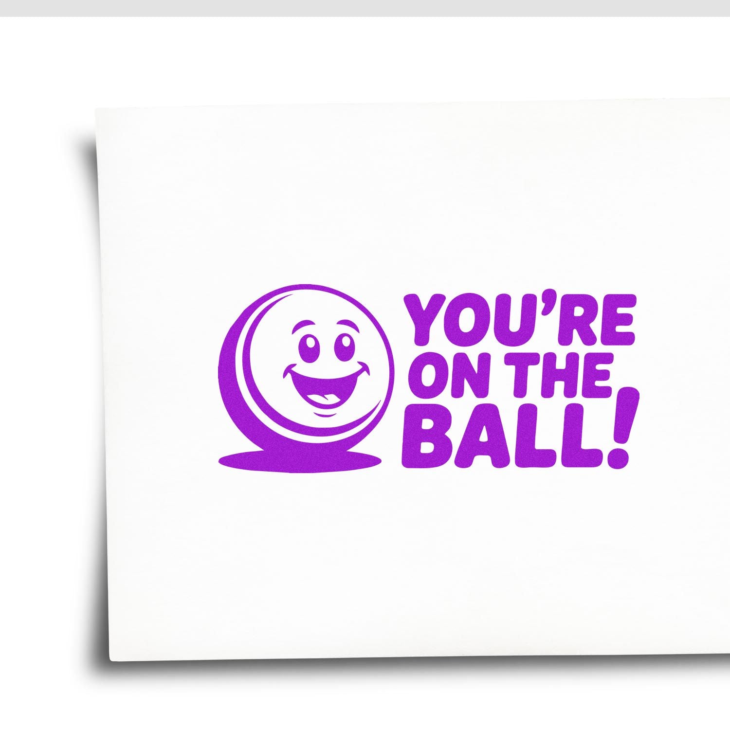 Purple stamp and seal with smiling ball icon and bold text, YOURE ON THE BALL! on white background.