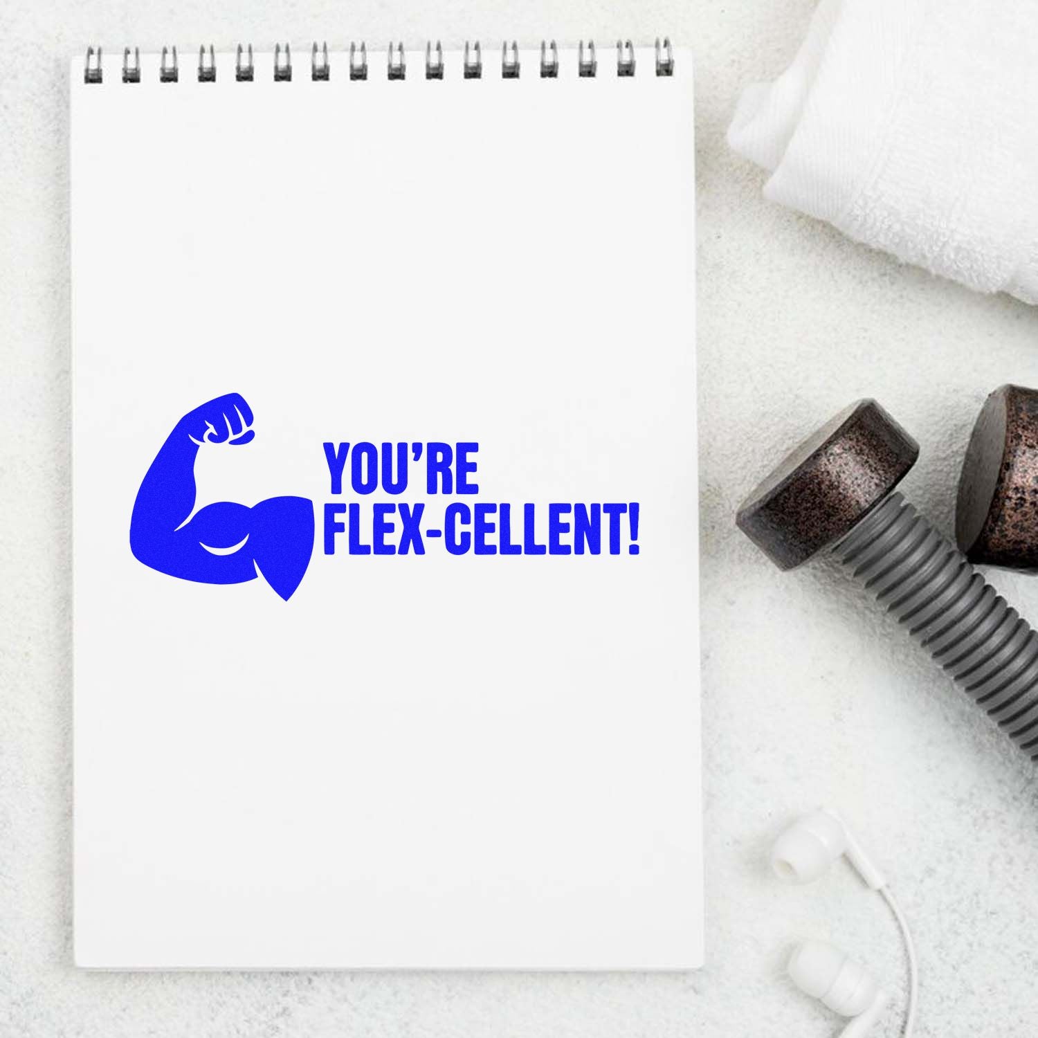 Blue YOURE FLEX-CELLENT! flexing arm stamp on white notepad, beside rusted seal hardware and bolt components.