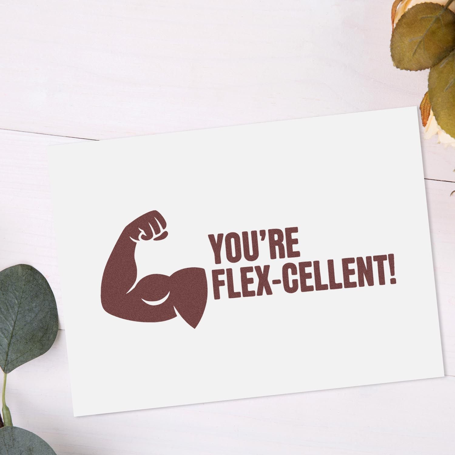 Brown custom stamp seal with flexed arm and YOURE FLEX-CELLENT! on a white card, with soft greenery accents.